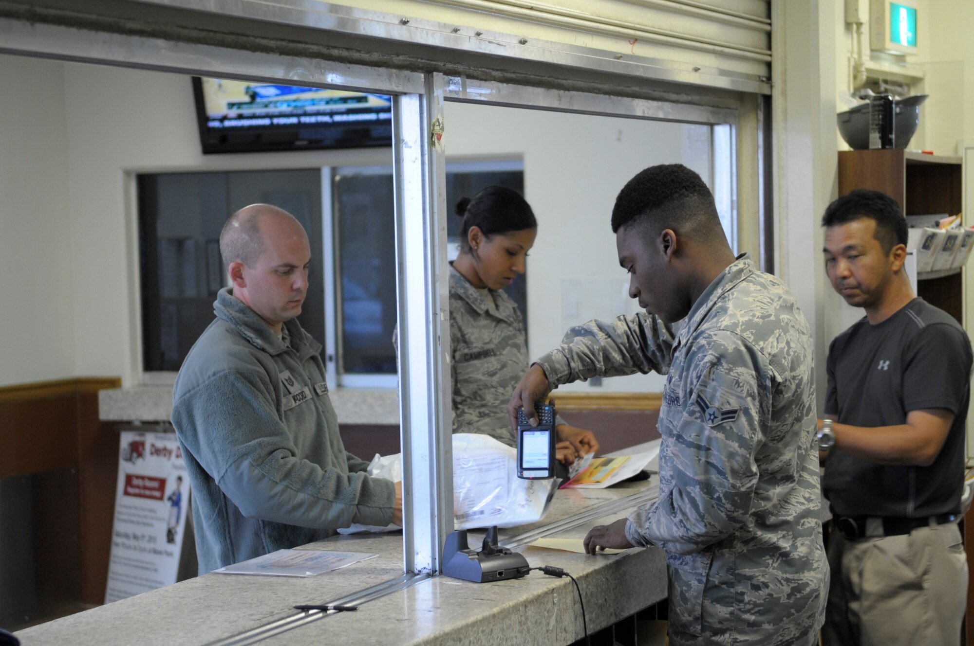 U.S. Air Force Airman 1st Class Marcus Williams, 18th Communications Squadron postal worker, assists a customer on Kadena Air Base, Japan, March 5, 2015. Kadena’s post office, the Air Force's 2014 Best Large Post Office of the year, processes 23 million pounds of postage throughout the year.