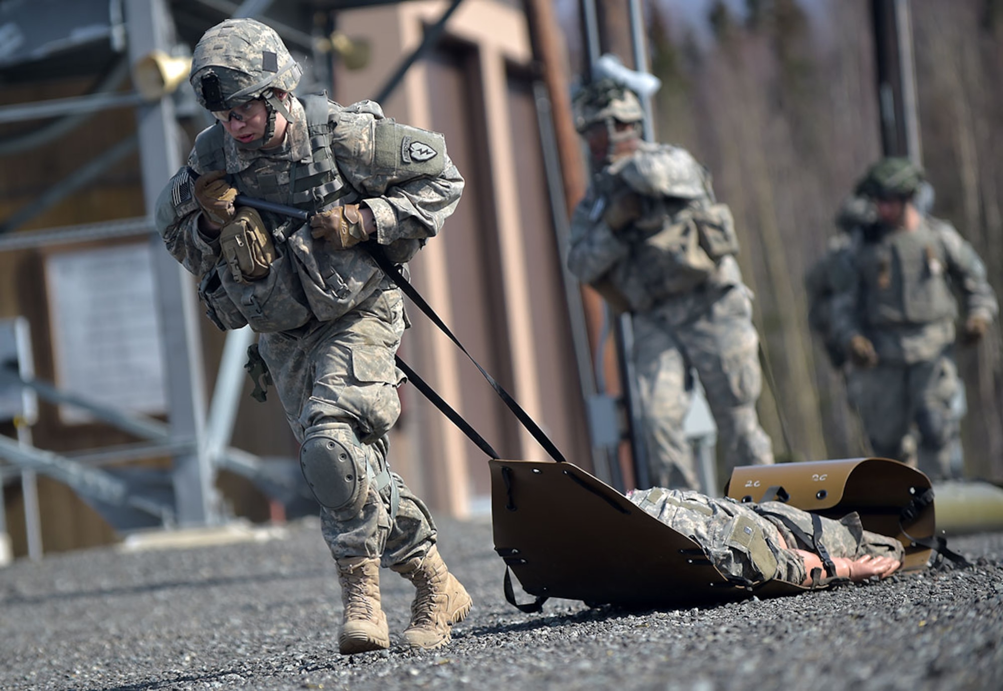 Gilbert pulls a simulated casualty away from his fighting position. Stress-fire exercises involve Soldiers running, crawling, and performing other battle tasks to increase their heart rates and mental stress, before manning a weapon and shooting accurately. The training mimics combat situations, so when troops are in a combat situation, they are already familiar with the mental and physical drain – and can perform well despite the challenges. Noncommissioned officers mentor younger troops while pushing them to their limits. (U.S. Air Force photos/Justin Connaher)
