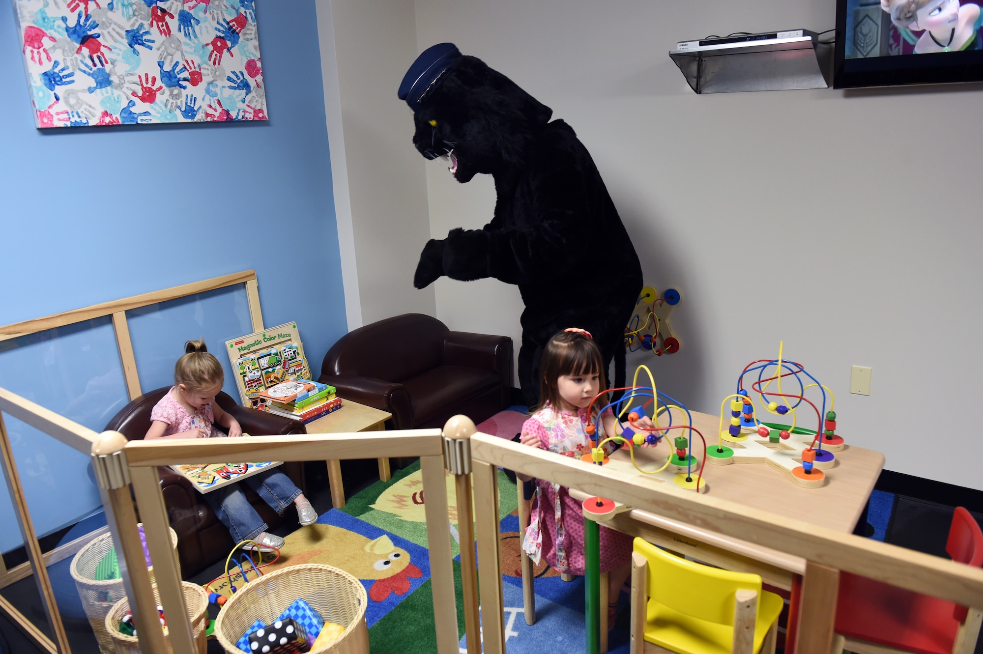 Buck Lee, 460th Space Wing mascot, plays with children in the new Cub Corral April 30, 2015, in the fitness center on Buckley Air Force Base, Colo. The Cub Corral is a new workout room for parents to exercise while providing a place for their children to play. This room fixes the challenges that parents previously faced with living a fit life while also finding child care at the same time. Along with the Cub Corral, the fitness center is also opening up the Buck Stop, a food bar that will provide protein shakes, coffee and other snacks. (U.S. Air Force photo by Airman 1st Class Emily E. Amyotte/Released)