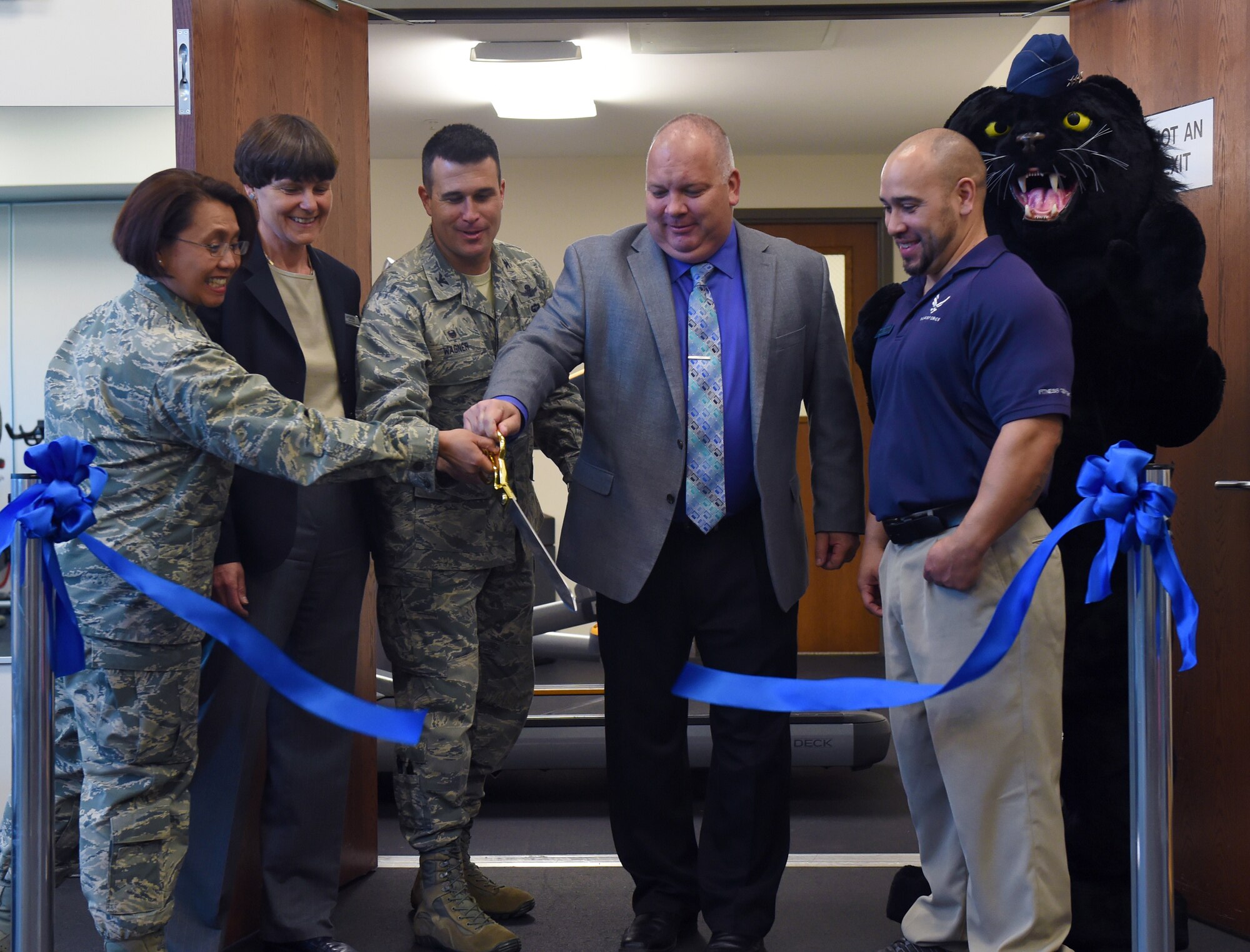 From left, Col. Rose Jourdan, 460th Mission Support Group commander; Debra Ponzio, 460th Force Support Squadron Communication and Sustainment Services flight chief; Col. John Wager, 460th Space Wing commander; Albert Woolley, 460th FSS Director; Bobby Padia, Buckley Fitness Center fitness and sports chief; and Buck Lee, 460th Space Wing mascot; cut the ribbon to the new Cub Corral April 30, 2015, in the fitness center on Buckley Air Force Base, Colo. The Cub Corral is a new workout room for parents to exercise while providing a place for their children to play. This room fixes the challenges that parents previously faced with living a fit life while also finding child care at the same time. Along with the Cub Corral, the fitness center is also opening up the Buck Stop, a food bar that will provide protein shakes, coffee and other snacks. (U.S. Air Force photo by Airman 1st Class Emily E. Amyotte/Released)