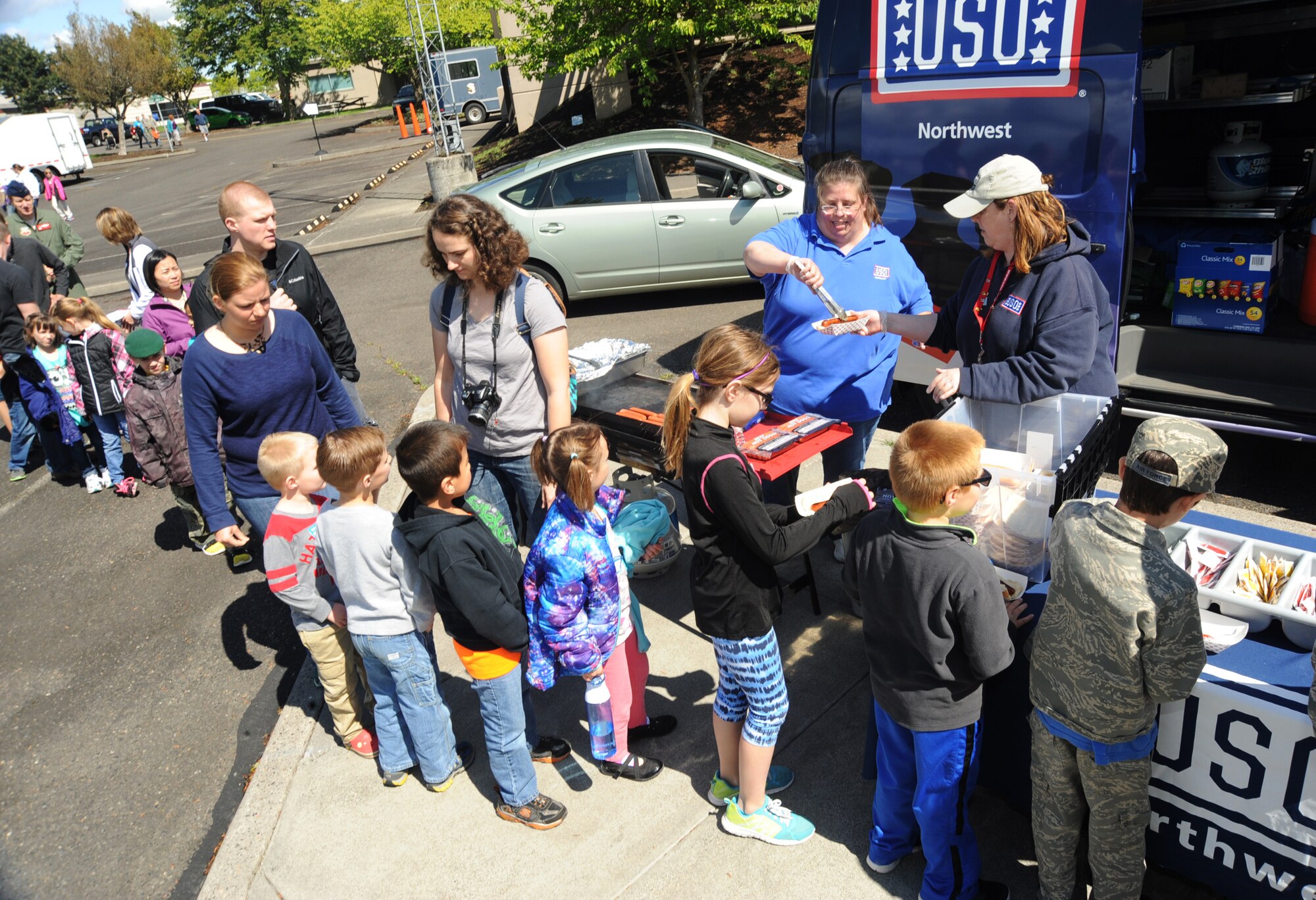 Volunteers from the Unites States Organization (USO) Debbie McDonald and Kristie King prepare and hand out hot dogs and other snacks to kids and families attending ‘Kids Day at PANG,” April 25, 2015, Portland Air National Guard Base, Ore. The Oregon National Guard opened the Portland Air Base to children of military members for a special day of activities highlighting “The Month of the Military Child,” designated since 1986 by the Department of Defense as way to recognize the contribution and personal sacrifices children make to the military. (U.S. Air National Guard photo by Tech. Sgt. John Hughel, 142nd Fighter Wing Public Affairs/Released)