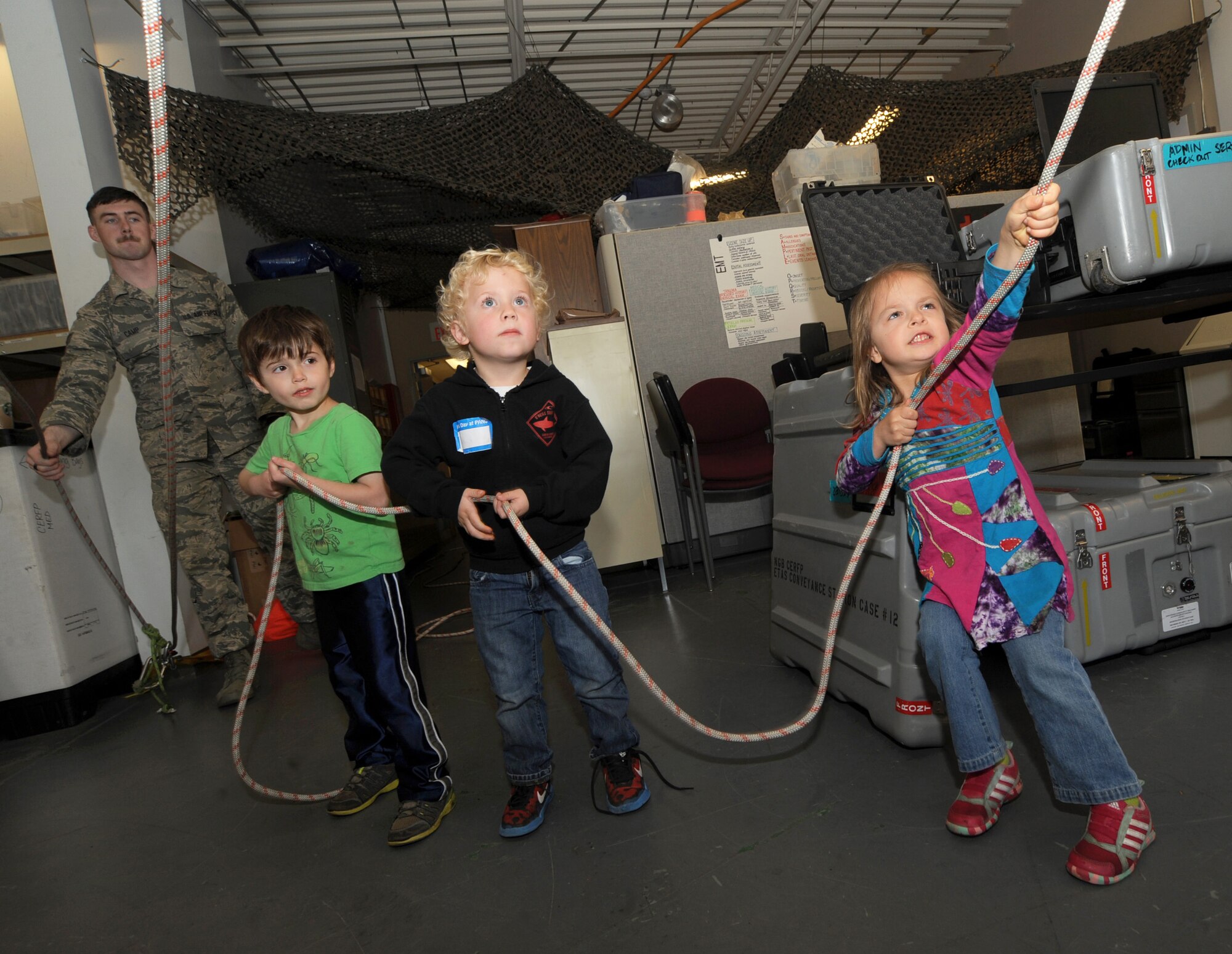 A group of kids use a pulley system to help lift others in rescue gear while attending ‘Kids Day at PANG’ April 25, 2015, personnel at the Portland Air National Guard Base, Ore.  The Oregon National Guard opened the Portland Air Base to children of military members for a special day of activities highlighting “The Month of the Military Child,” designated since 1986 by the Department of Defense as way to recognize the contribution and personal sacrifices children make to the military. (U.S. Air National Guard photo by Tech. Sgt. John Hughel, 142nd Fighter Wing Public Affairs/Released)