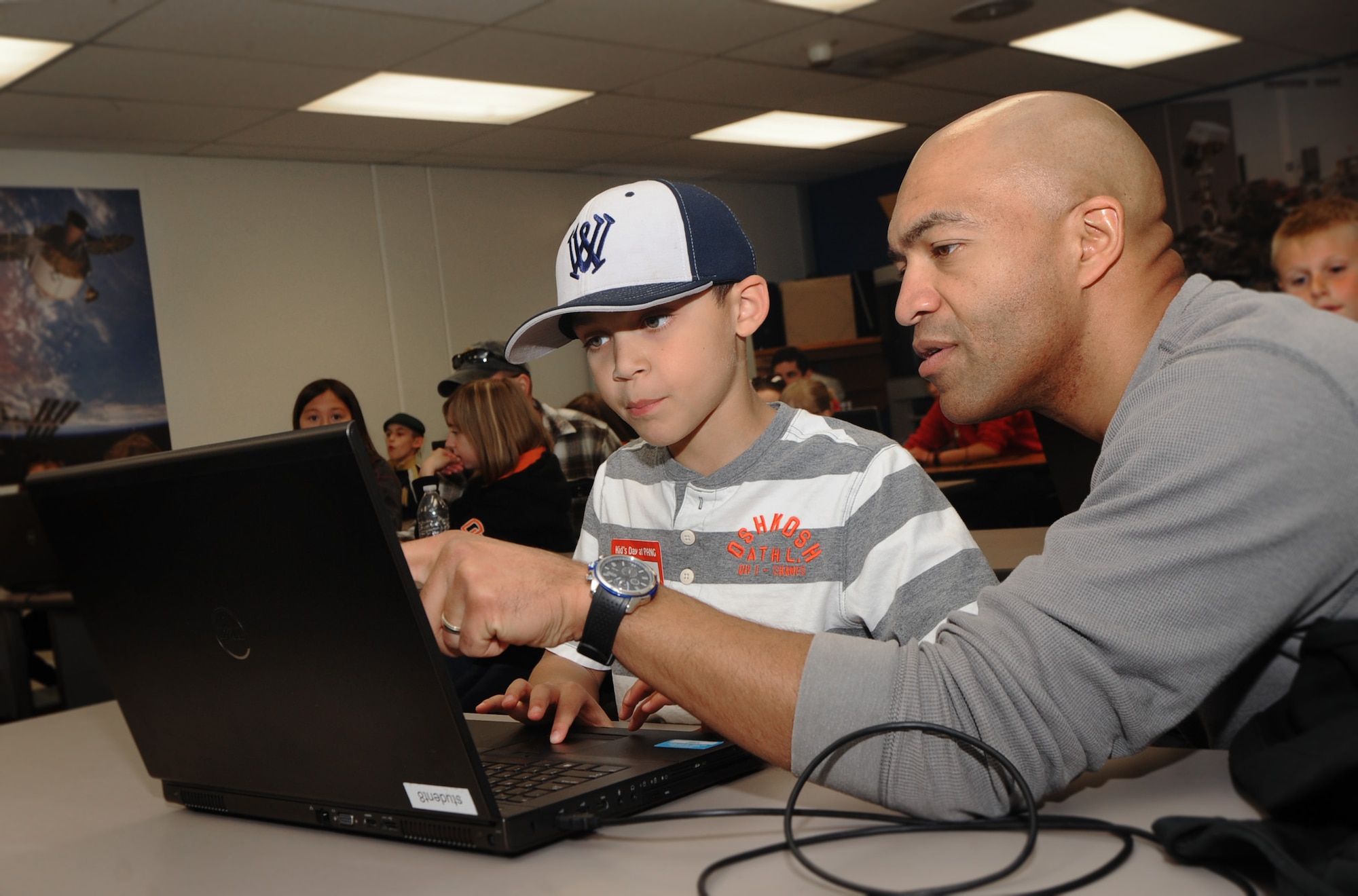 Oregon Air National Guard Senior Airman Brain Zimmerman, assigned to Joint Forces Headquarters, Salem, Ore., helps his son Trent program a robot at STARBASE, during ‘Kids Day at PANG’, April 25, 2015, Portland Air National Guard Base, Ore. The Oregon National Guard opened the Portland Air Base to children of military members for a special day of activities highlighting “The Month of the Military Child,” designated since 1986 by the Department of Defense as way to recognize the contribution and personal sacrifices children make to the military. (U.S. Air National Guard photo by Tech. Sgt. John Hughel, 142nd Fighter Wing Public Affairs/Released)