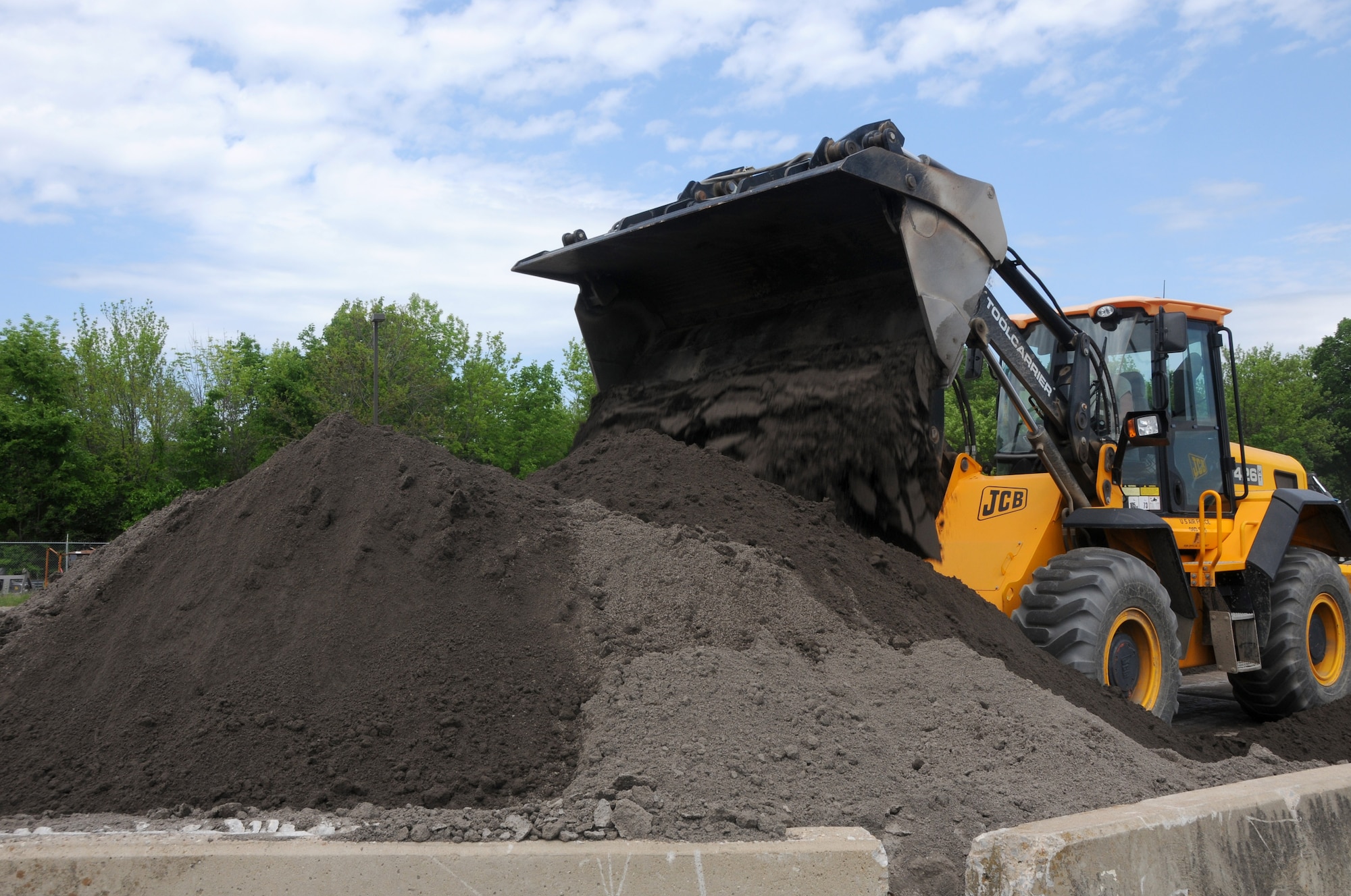 Master Sgt. Bryan Sutton, 188th Civil Engineer Squadron member, unloads crusher dust from a front-end loader during asphalt traiing at Ebbing Air National Guard Base, Fort Smith, Ark., April 21, 2015. The 188th Rapid Engineer Deployable Heavy Operational Repair Squadron Engineer training center provided asphalt training from April 21-24.(U.S. Air National Guard photo by Senior Airman Cody Martin/released)