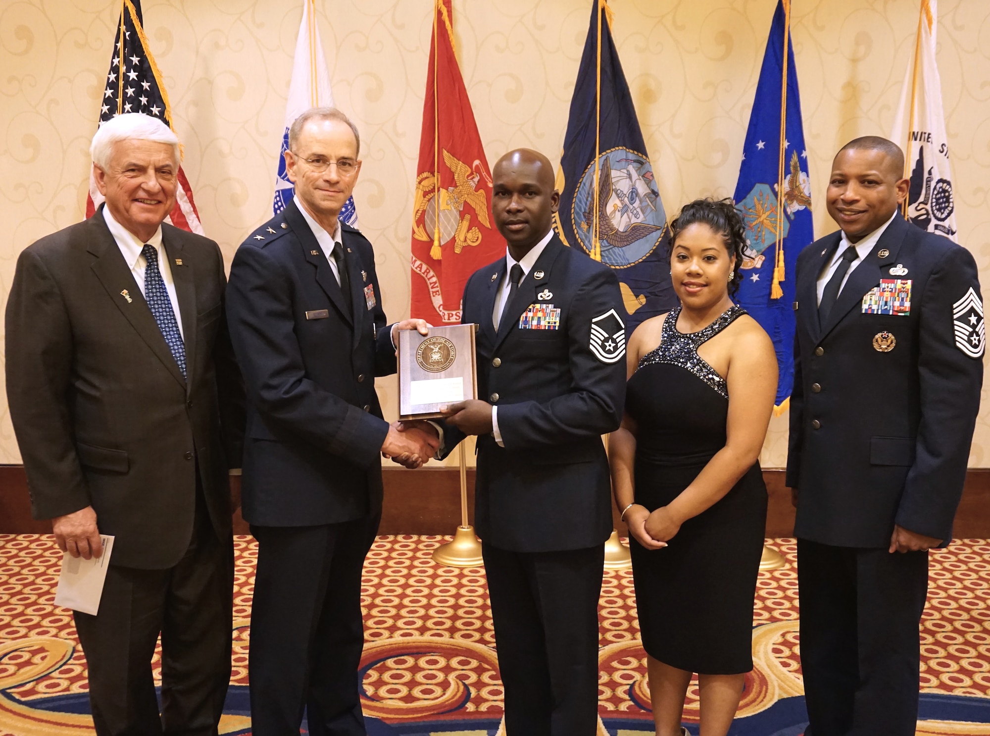 Master Sgt. Keval A. Smith, 45th Civil Engineer Squadron, NCO in charge of unit safety and vehicle control, center, receives the 2014 Government Employees Insurance Company Military Service Award for the Air Force with his wife Sabrina, right of Smith, from Maj. Gen. (Dr.) Mark Ediger, Deputy Surgeon General for the Air Force. Also pictured are GEICO Chairman Tony Nicely, left, and Chief Master Sgt. Farrell Thomas, Air Force District of Washington command chief, right. (Courtesy photo by GEICO)