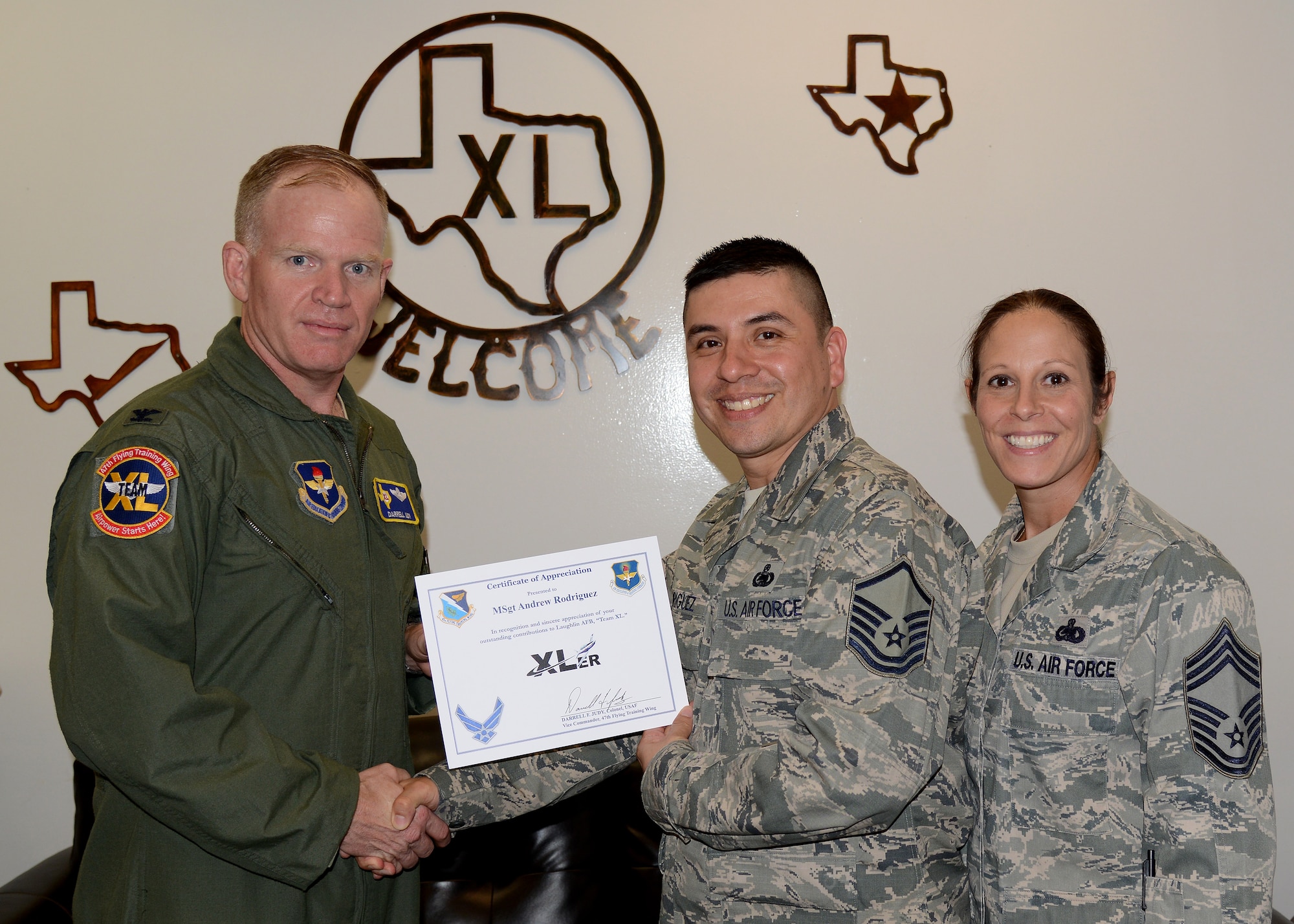 Master Sgt. Andrew Rodriguez, center, 47th Logistics Readiness Flight Supply Contracting Officer representative and superintendent, poses with Col. Darrell Judy, 47th Flying Training Wing vice commander, and Chief Master Sgt. Patricia Hickey, 47th Mission Support Group superintendent, after accepting the XLer of the Week award here April 22, 2015. The XLer is a weekly award chosen by wing leadership and is presented to those who consistently make outstanding contributions to their unit and Laughlin. (U.S. Air Force photo by Airman 1st Class Ariel D. Partlow)(Released)