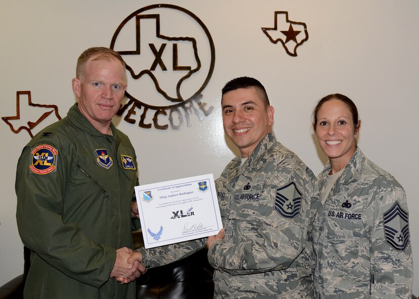Master Sgt. Andrew Rodriguez, center, 47th Logistics Readiness Flight Supply Contracting Officer representative and superintendent, poses with Col. Darrell Judy, 47th Flying Training Wing vice commander, and Chief Master Sgt. Patricia Hickey, 47th Mission Support Group superintendent, after accepting the XLer of the Week award here April 22, 2015. The XLer is a weekly award chosen by wing leadership and is presented to those who consistently make outstanding contributions to their unit and Laughlin. (U.S. Air Force photo by Airman 1st Class Ariel D. Partlow)(Released)