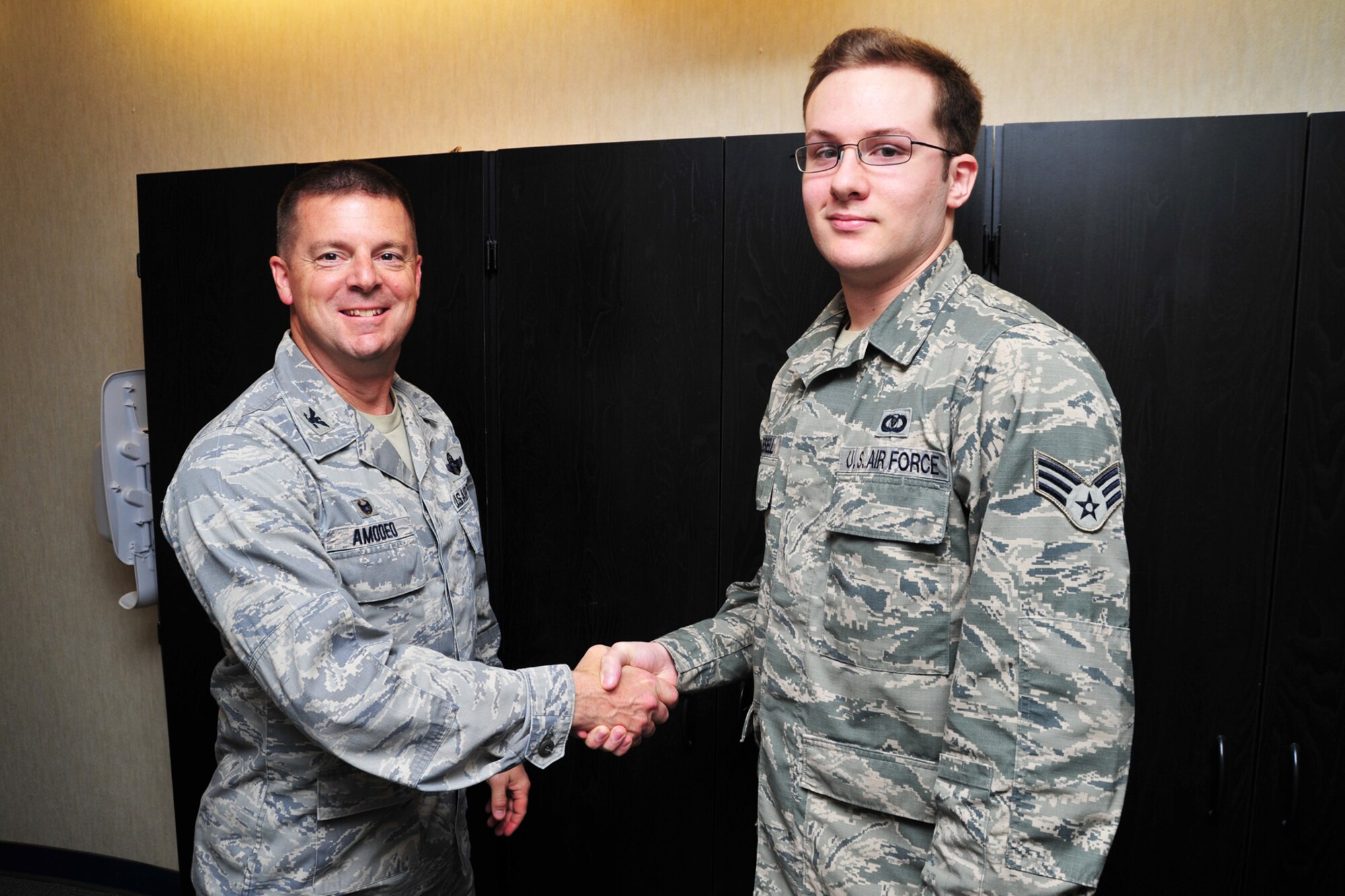 Col. Frank Amodeo, 403rd Wing commander, presents a command coin April 12, 2015, to Senior Airman Preston Mikesell, 81st Training Wing command post senior emergency actions controller, for his efforts in arranging for 403rd reservists to arrive at Keesler Air Force Base, Mississippi, during a training mission. Mikesell helped coordinate an aircraft divert to MacDill AFB, Florida, to keep training on track. (U.S. Air Force photo/Tech. Sgt. Ryan Labadens)
