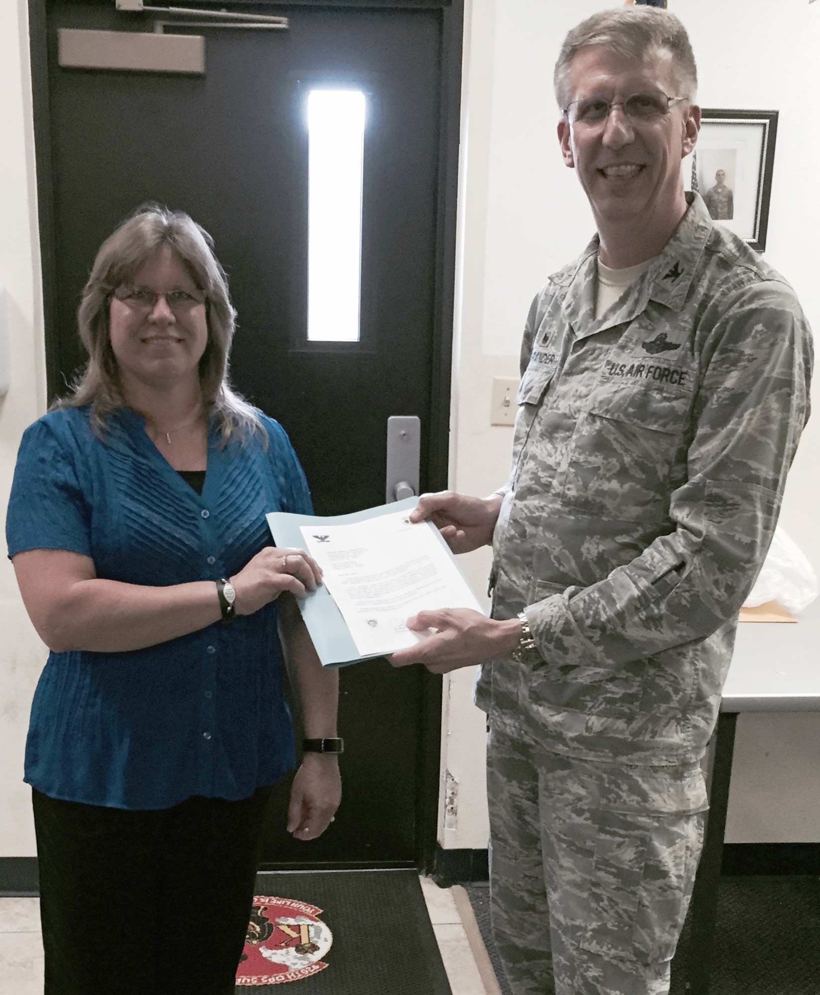 Jennifer Davis (left), the wife of Lt. Col. Tim Davis, 920th Operational Support Squadron commander, was recognized by both the 45 Space Wing and the 920 Rescue Wing April 25 during the 920th RQW’s weekend training assembly for logging more than 2,500 volunteer service hours among both of the Air Force wings at Patrick Air Force Base, Florida. Col. Jeffrey Macrander, 920th Rescue Wing commander, presented Davis with a certificate and an eagle statue. (Courtesy photo)