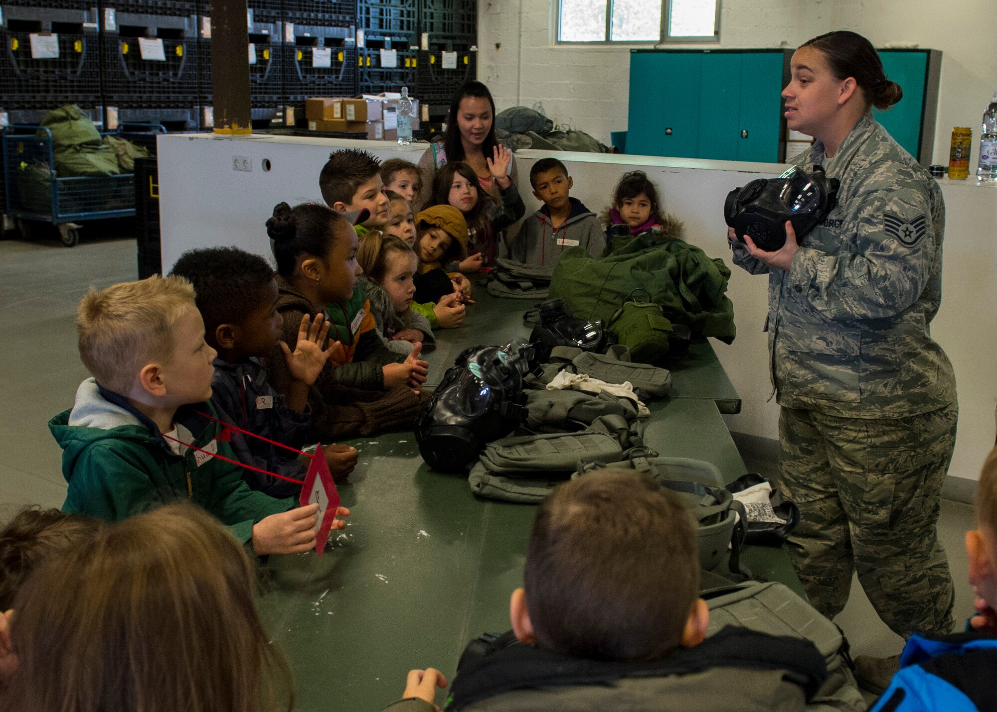 U.S. Air Force Staff Sgt. Amy Dietrich, 52nd Logistics Readiness Squadron document control NCO in charge, explains the use of mission-oriented protective posture gear to students of Spangdahlem Elementary School during Kids’ Deployment Day at Spangdahlem Air Base, Germany, April 29, 2015. The simulated deployment consisted of four different stations including vehicles, equipment, safety information and air transportation. (U.S. Air Force photo by Airman 1st Class Luke Kitterman/Released)   
