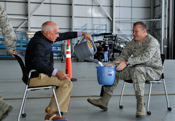U.S. Air Force Col. Kenneth T. Bibb, Jr., right, 100th Air Refueling Wing commander, receives simulated fuel from Ken Thompson, left, British American Council chairman, as part of a challenge during Honorary Commanders’ Day April 28, 2015, on RAF Mildenhall, England. The day consisted of many team building challenges which provided a better understanding of the role and mission of the U.S. Air Force. (U.S. Air Force photo by Airman 1st Class Kyla Gifford/Released)