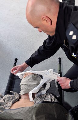 Inspector Matthew Rose, local policing commander for the Forest Heath District and the 100th Security Forces Squadron honorary commander, performs self-aid buddy care as part of a challenge during Honorary Commanders’ Day April 28, 2015, on RAF Mildenhall, England. Throughout the day, honorary commanders and their sponsors participated in competitive team building events, viewed aircraft and met with Airmen. (U.S. Air Force photo by Airman 1st Class Kyla Gifford/Released)
