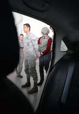 U.S. Air Force Senior Airman Angel Trejo, 100th Security Forces Squadron response force leader, stands while Kevin Ward, 100th Comptroller Squadron outgoing honorary commander hand cuff’s him April 28, 2015, during the Honorary Commander’s Day event on RAF Mildenhall, England. Base leadership and honorary commanders participated in several competitive team building events as a way for them to better understand RAF Mildenhall’s overall mission. (U.S. Air Force photo by Senior Airman Christine Halan/Released)
