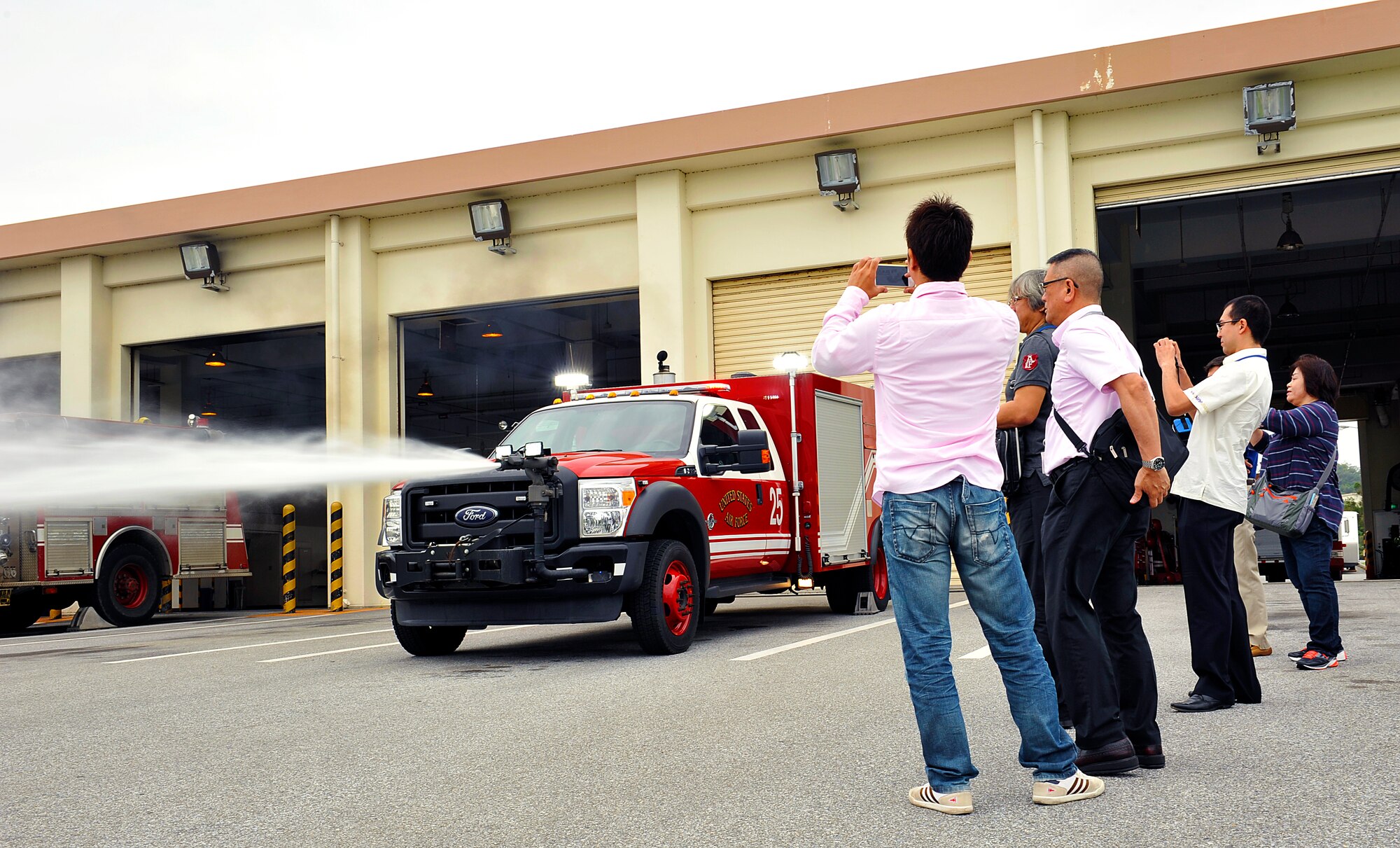 Members from the Civil Aviation Bureau, Naha Airport, take pictures of a rapid intervention vehicle and Tadashi Sakima, 18th Civil Engineer Squadron driver operator, during a demonstration on Kadena Air Base, Japan, April 29, 2015. The visit focused on fostering community relations, a cross-flow of information and strengthening the Future Farmers of America, Department of Defense, and International Fire Service Accreditation Congress understanding. (U.S. Air Force photo by Naoto Anazawa)
