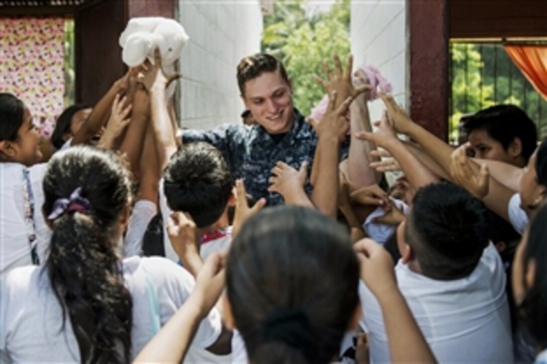 U.S. Navy Seaman Schuyler Nesbitt gives Guatemalan children stuffed animals at the Maria Luisa III School during a community service event in support of Continuing Promise 2015 in Puerto Barrios, Guatemala, April 23, 2015.