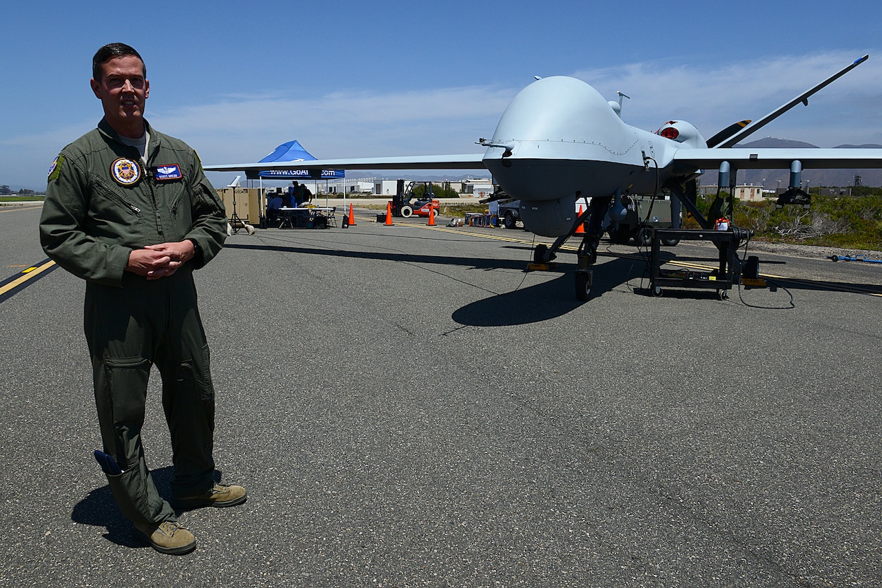 Air Force Maj. Scott Gregg, Black Dart project officer, speaks to the media in front of a MQ-9 unmanned aircraft system, at Naval Base Ventura County and Sea Range, Point Mugu, Calif., July 31, 2015. The drone, Gregg said, is in the largest categories of UASs, or Group 5, flies at more than 18,000 feet in altitude and weighs more than 1,300 pounds. It was being used as part of the two-week Black Dart counter-UAS demonstration, July 26 to Aug. 7, to assess and improve technologies, tactics and techniques used by DoD and its partners. DoD photo by Lisa Ferdinando