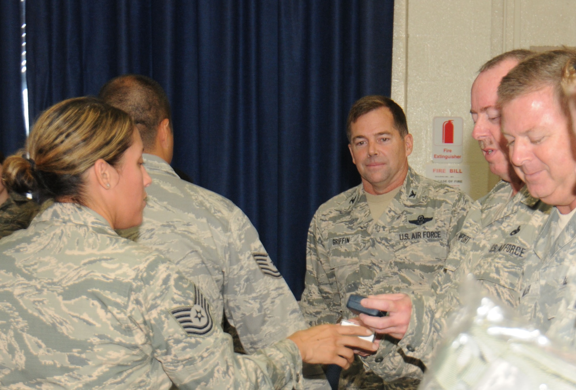 Col.William Griffin, 111th Attack Wing vice commander, watches as coins are being given to 111 ATKW members who recently re-enlisted, Aug. 1, 2015, Horsham Air Guard Station, Pennsylvania. The coins, along with other items, were formally presented by the 111th ATKW Strength Management Team during the commander's call of this month's unit training assembly. (U.S. Air National Guard photo by Tech. Sgt. Andria Allmond/Released)