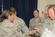 Col.William Griffin, 111th Attack Wing vice commander, watches as coins are being given to 111 ATKW members who recently re-enlisted, Aug. 1, 2015, Horsham Air Guard Station, Pennsylvania. The coins, along with other items, were formally presented by the 111th ATKW Strength Management Team during the commander's call of this month's unit training assembly. (U.S. Air National Guard photo by Tech. Sgt. Andria Allmond/Released)