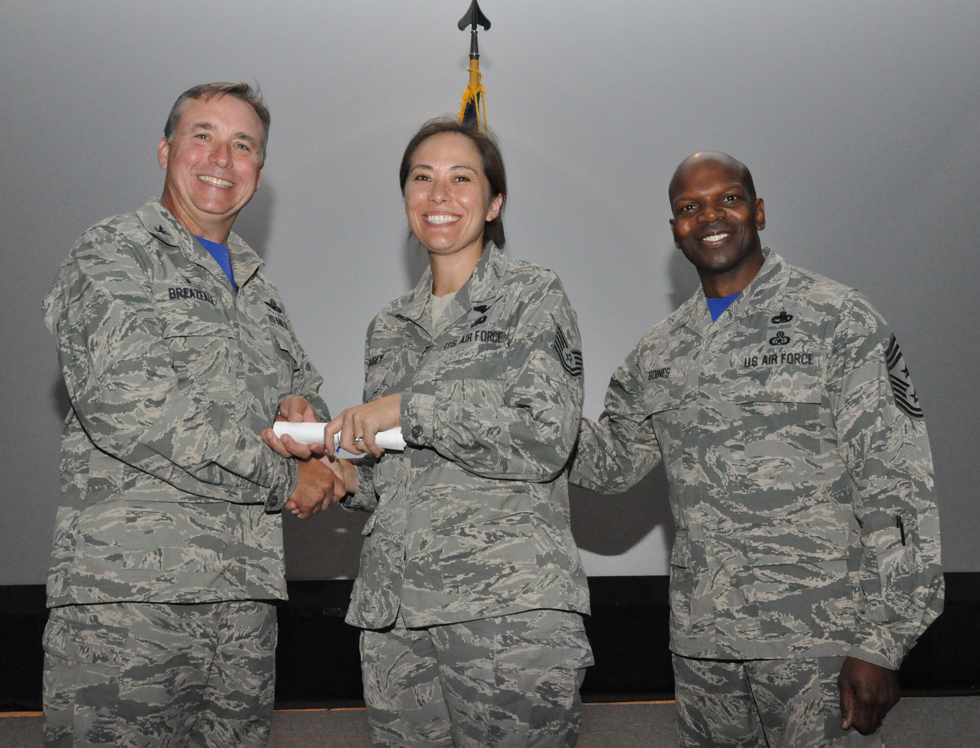 NAVAL AIR STATION FORT WORTH JOINT RESERVE BASE, Texas - 301st Fighter Wing Commander John Breazeale (left) and Chief Master Sgt. Terry Goines, wing command chief (right), award Tech. Sgt. Myrna Trubey, a chaplain assistant, her Community College of the Air Force degree in social services during a graduation ceremony Aug. 1 at the base theater here. More than 20 graduates participated in the event. (U.S. Air Force photo/Staff Sgt. Melissa Harvey)