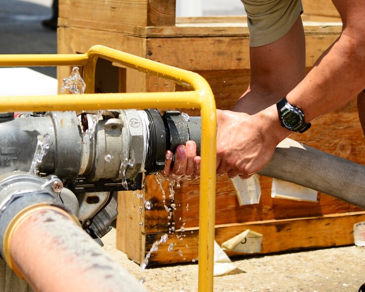 U.S. Air Force Staff Sgt. Nicholas Lezza, 387th Civil Engineer Squadron firefighter, attaches a firehose to a pump at an undisclosed location in Southwest Asia, July 30, 2015. Fire Protection training involves learning how to use fire protection equipment, rescue principles and procedures and standard first aid, which aids in support of Operation INHERENT RESOLVE. (U.S. Air Force photo by Senior Airman Racheal E. Watson/Released)