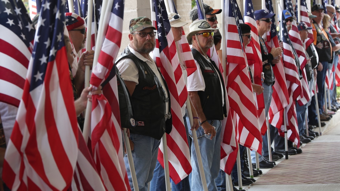 Service members, veterans and civilians hold American flags as they stand outside the First Baptist Church of Woodstock entrance, waiting for Lance Cpl. Squire “Skip” Wells’ casket to arrive July 26, 2015 in Woodstock, Georgia. Wells was one of five service members killed during a shooting at the Naval Operational Support Center and Marine Corps Reserve Center on July 16, 2015. More than a thousand people attended the funeral service to pay their respects and show support to Wells and his family.