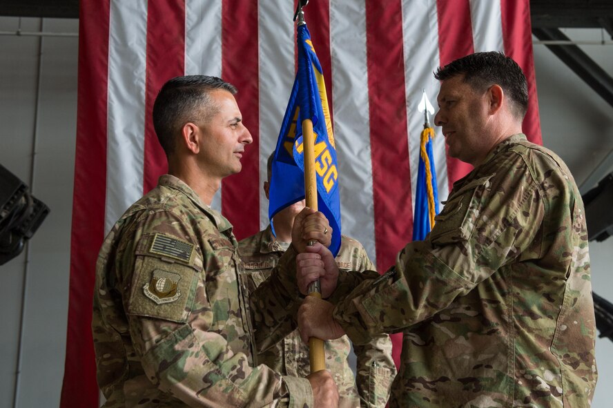 U.S. Air Force Brig. Gen. Dave Julazadeh, 455th Air Expeditionary Wing commander, hands the guidon to Col. William Clark, 455th Expeditionary Mission Support Group incoming commander, during the 455th EMSG change of command ceremony at Bagram Airfield, Afghanistan, Aug. 3, 2015. The 455th MSG is comprised of five squadrons responsible for communications, civil engineer operations, force support, logistics readiness, and security forces. (U.S. Air Force photo by Tech. Sgt. Joseph Swafford/Released)