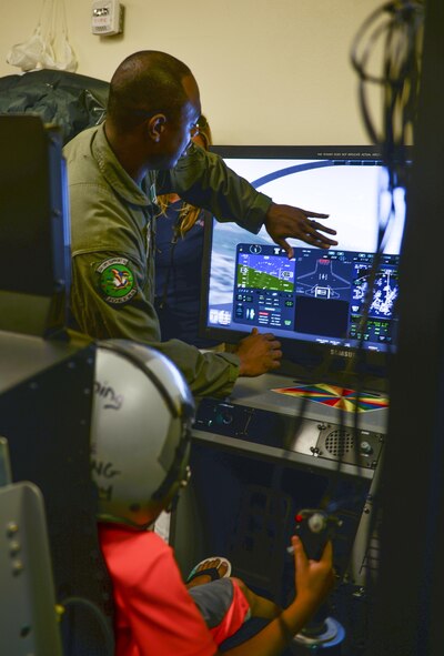 Tech. Sgt. Omar Robinson, 96th Test Wing aerospace and operations physiological technician, shows a child how to operate a flight simulator for “Bring your family to work day” at Eglin Air Force Base, Fla., July 31, 2015. The 33 OSS and 58 FS hosted this event to show families their jobs in the Air Force. (U.S. Air Force Photo/Senior Airman Andrea Posey)