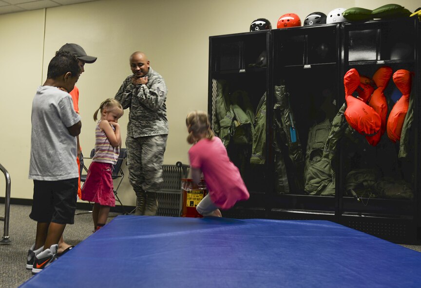 Staff Sgt. Edwin Portan, 33rd Operations Support Squadron aircrew flight equipment continuation training instructor, shows children how to land during a parachute landing for “Bring your family to work day” at Eglin Air Force Base, Fla., July 31, 2015. The 33 OSS and 58 FS hosted this event to show families their jobs in the Air Force. (U.S. Air Force Photo/Senior Airman Andrea Posey)