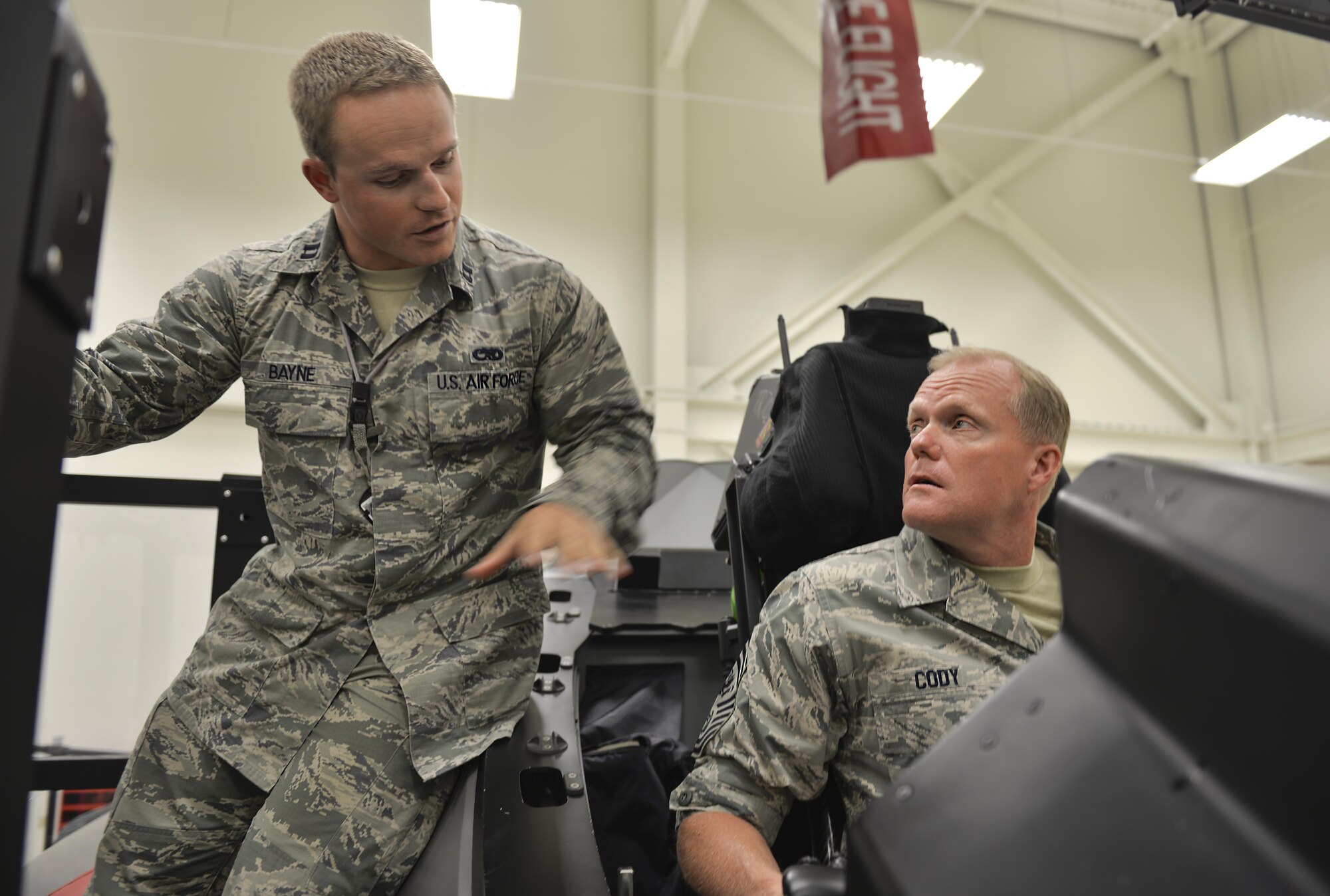 Capt. Charles Bayne, 359th Training Squadron F-35 maintenance training lead, explains the mechanics of an F-35 Lightening II cockpit to Chief Master Sgt. of the Air Force James Cody at Eglin Air Force Base, Fla., July 30, 2015. Cody visited Eglin AFB to touch base with Airmen in the 33rd Fighter Wing and the 96th Force Support Squadron. (U.S. Air Force Photo/Senior Airman Andrea Posey)