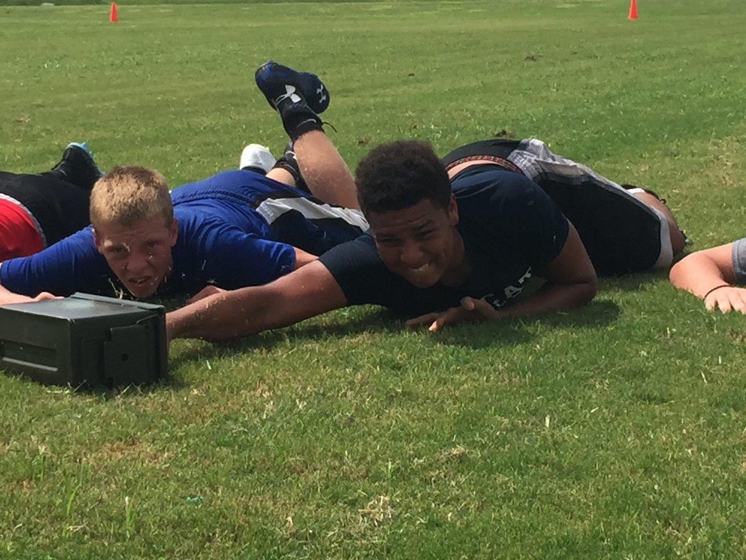 Football players from Wesley Chapel High School push an ammo can during the tactical decision game portion of the leadership seminar put on by local Marines July 30, 2015, at Wesley Chapel High School. The seminar teaches athletes about Marine Corps leadership traits and principles. 
