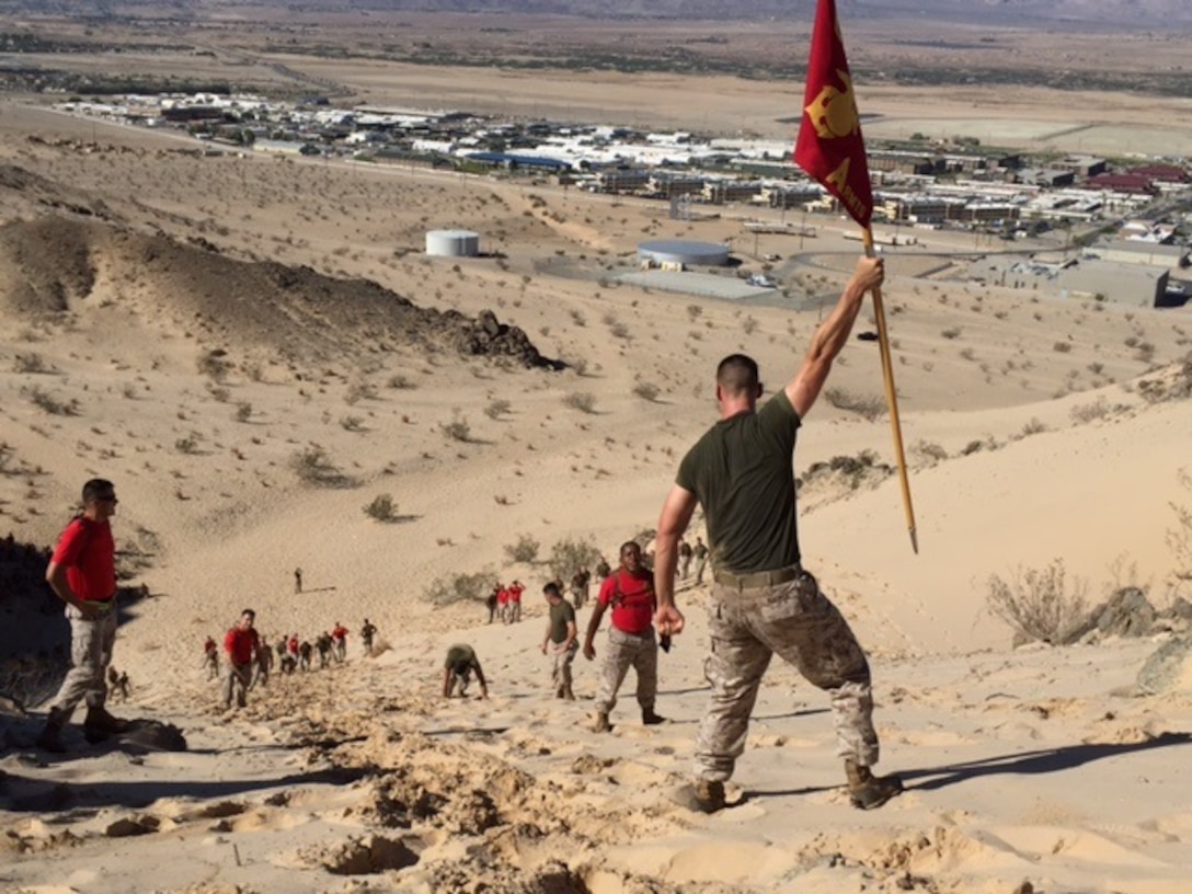 LCpl Boomer from Digital Wideband Repair Course 3-15 raises the section guide-on in victory during the final event of the RMTS Challenge.  Classes competed against each other through various combat simulated scenarios that tested their strength, stamina, and speed along with mentally agility.