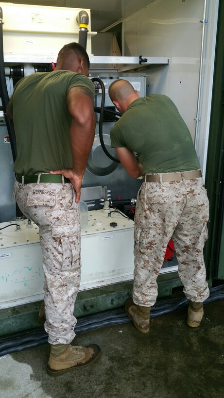 Sgt Wennberg, an instructor for BWST 7-15; looks on as a Marine from BWST 7-15 conducts a practical application on Containerize Batch Laundry (CBL) unit.
