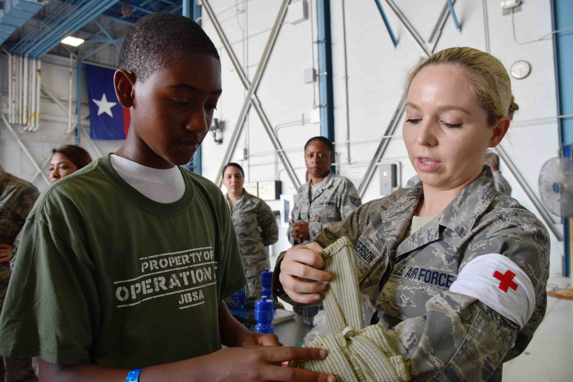 Blake Taylor applies a pressure bandage to Tech. Sgt. Cassandra Dickerson, 433rd Aeromedical Staging Squadron, after learning the proper technique from her and why it is used. Taylor was one of 200 children who participated in Operation JET at Joint Base San Antonio-Lackland, Texas on July 31, 2015. (U.S. Air Force photo/Tech. Sgt. Carlos J. Trevino)