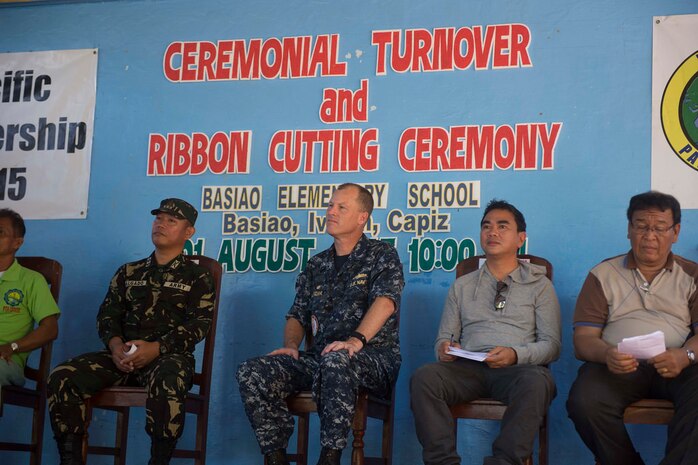 BASIAO, Philippines (August 1, 2015) - Pacific Partnership (PP) 2015 Mission Commander Capt. Chris Engdahl sits with members of the official party at a ribbon cutting ceremony at Basiao Elementary School. A team of U.S. Navy Seabees and U.S. Air Force RED HORSE engineers from the hospital ship USNS Mercy (T-AH 19), rebuilt parts of the school that had been damaged in Hurricane Yolanda. Mercy is in the Philippines for its third mission port of PP 2015. Pacific Partnership is in its 10th iteration and is the largest annual multilateral humanitarian assistance and disaster relief preparedness mission conducted in the Indo-Asia-Pacific region. While training for crisis conditions, PP missions to date have provided real world medical care to approximately 270,000 patients and veterinary services to more than 38,000 animals. Critical infrastructure development has been supported in host nations during more than 180 engineering projects. 