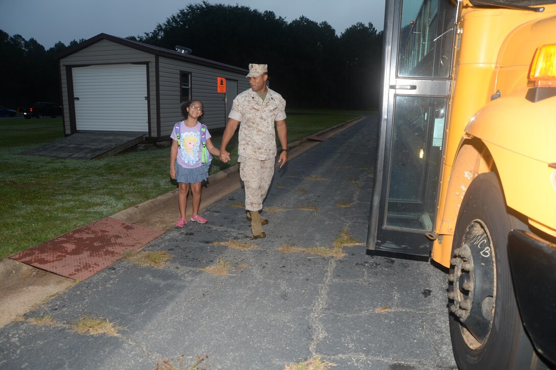 A Marine escorts his daughter to the bus on her first day of school.