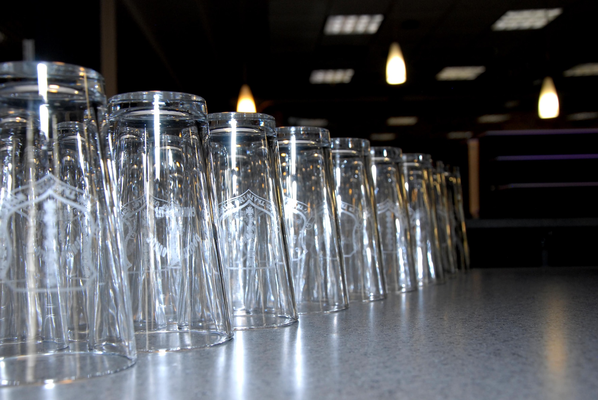Commemorative glasses sit on the counter the Doolittle Lounge reopening on Goodfellow Air Force Base, Texas, July 31, 2015.These glasses, featuring the 17th Training Wing’s emblem, were given to the first 100 customers. (U.S. Air Force photo by Senior Airman Joshua Edwards/Released)