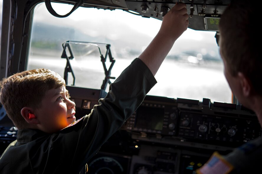 Pilot For A Day Eddie Paul Bearb runs through his pre-flight checklist with U.S. Air Force Capt. Patrick Dixon in the cockpit of a USAF C-17 at Joint Base Pearl Harbor-Hickam, Hawaii, July 30, 2015. The 9 year old, who is battling Acute Lymphoblastic Leukemia, enjoyed a day living life as a 15th Wing 535th Airlift Squadron member as part of his Dreams Come True wish. (U.S. Air Force photo by 2nd Lt. Kaitlin Daddona/Released)