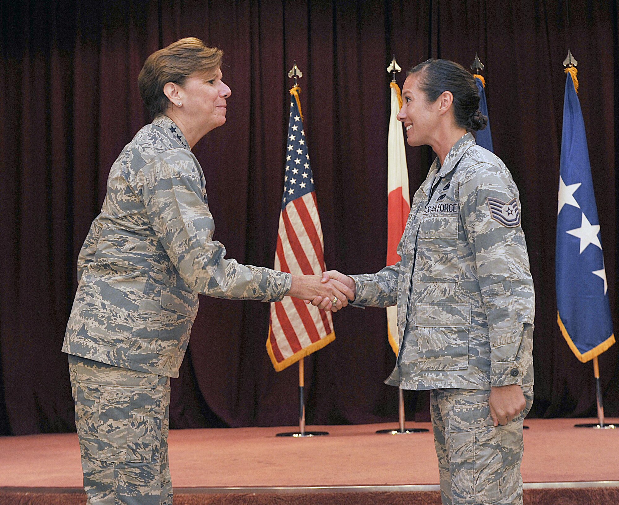U.S. Air Force Gen. Lori J. Robinson, Pacific Air Forces commander, coins U.S. Air Force Tech. Sgt. Angela Warren, 18th Logistics Readiness Squadron NCO in charge of plans, at the Kadena Officer's Club on Kadena Air Base, Japan, Aug. 3, 2015. During her two-day visit, the general addressed several issues that are important to her, including Airmen taking care of Airmen and the strategic shift to the Pacific. She also communicated her expectations with Kadena leaders. (U.S. Air Force photo by Naoto Anazawa/Released)