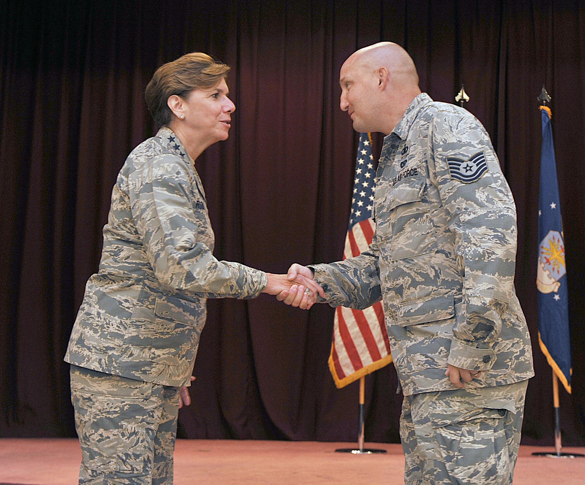 U.S. Air Force Gen. Lori J. Robinson, Pacific Air Forces commander, coins U.S. Air Force Tech. Sgt. Kevin Chellis, 18th Wing Chapel operations NCO in charge, at the Kadena Officer's Club on Kadena Air Base, Japan, Aug. 3, 2015. During her two-day visit, the general addressed several issues that are important to her, including Airmen taking care of Airmen and the strategic shift to the Pacific. She also communicated her expectations with Kadena leaders. (U.S. Air Force photo by Naoto Anazawa/Released)