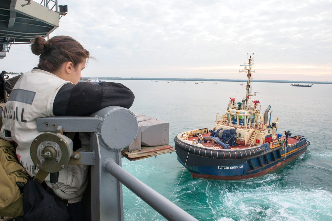 U.S. Navy Seaman Amber Greenwood watches as a tugboat assists the forward-deployed amphibious assault ship USS Bonhomme Richard as it leaves port in Darwin, Australia, July 27, 2015. Greenwood is a hospitalman. The Bonhomme Richard is the lead ship of the Bonhomme Richard Expeditionary Strike Group and is on patrol in the U.S. 7th Fleet area of operations.