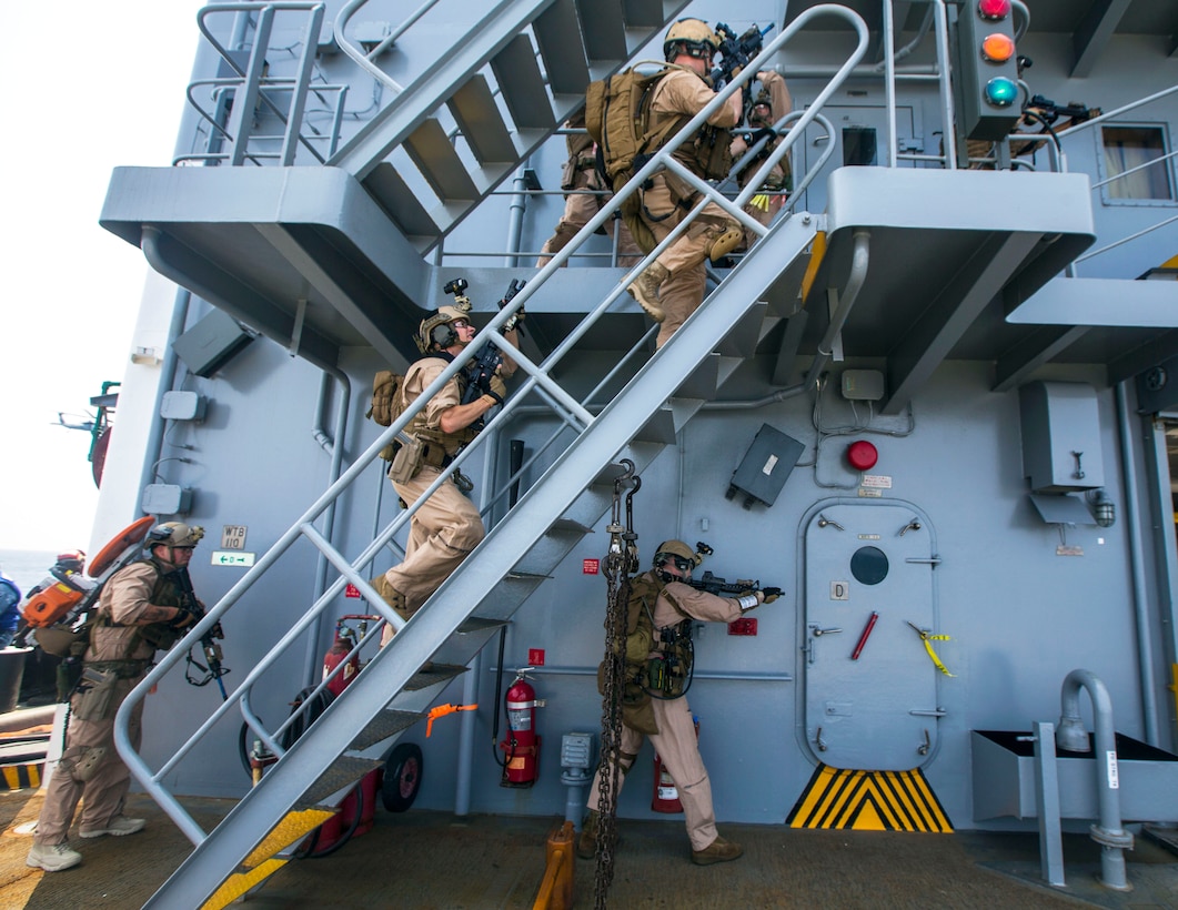 U.S. Marines climb a stairway and prepare to clear a ship while conducting a joint visit, board, search, and seizure exercise during composite training unit exercise, or COMPTUEX, in the Atlantic Ocean, July 20, 2015.