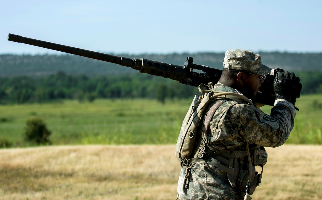 Army Reserve Spc. Dustin Willet carries the business end of an M2 Browning .50-caliber machine gun after familiarization training as part of Operation River Assault, a training exercise involving Army engineers and other support elements to create a modular bridge on the water across the Arkansas River on a gun range at Fort Chaffee, Ark., Aug. 2, 2015. Willet is an combat engineer assigned to the 346th Engineer Company, Route Clearance.