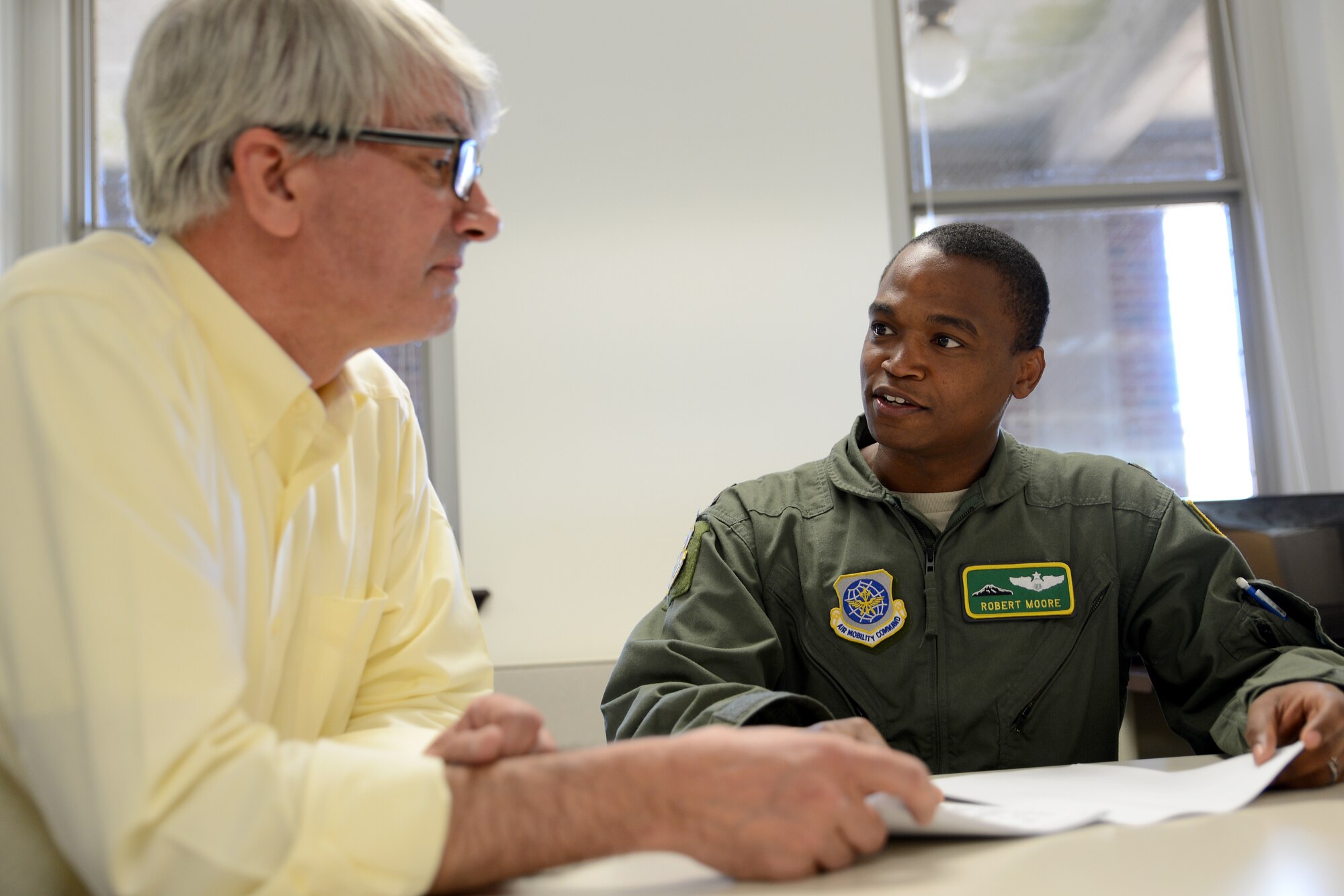 Maj. Robert Moore (right), 62nd Airlift Wing chief executive officer, talks to Joseph Bottero, 62nd Operations Support Squadron aviation resource management technician July 31, 2015, at Joint Base Lewis-McChord, Wash. Moore was selected for the General Benjamin O. Davis, Jr. Military Award for his efforts in leading crews operationally across the world. (U.S. Air Force photo/Airman 1st Class Keoni Chavarria)