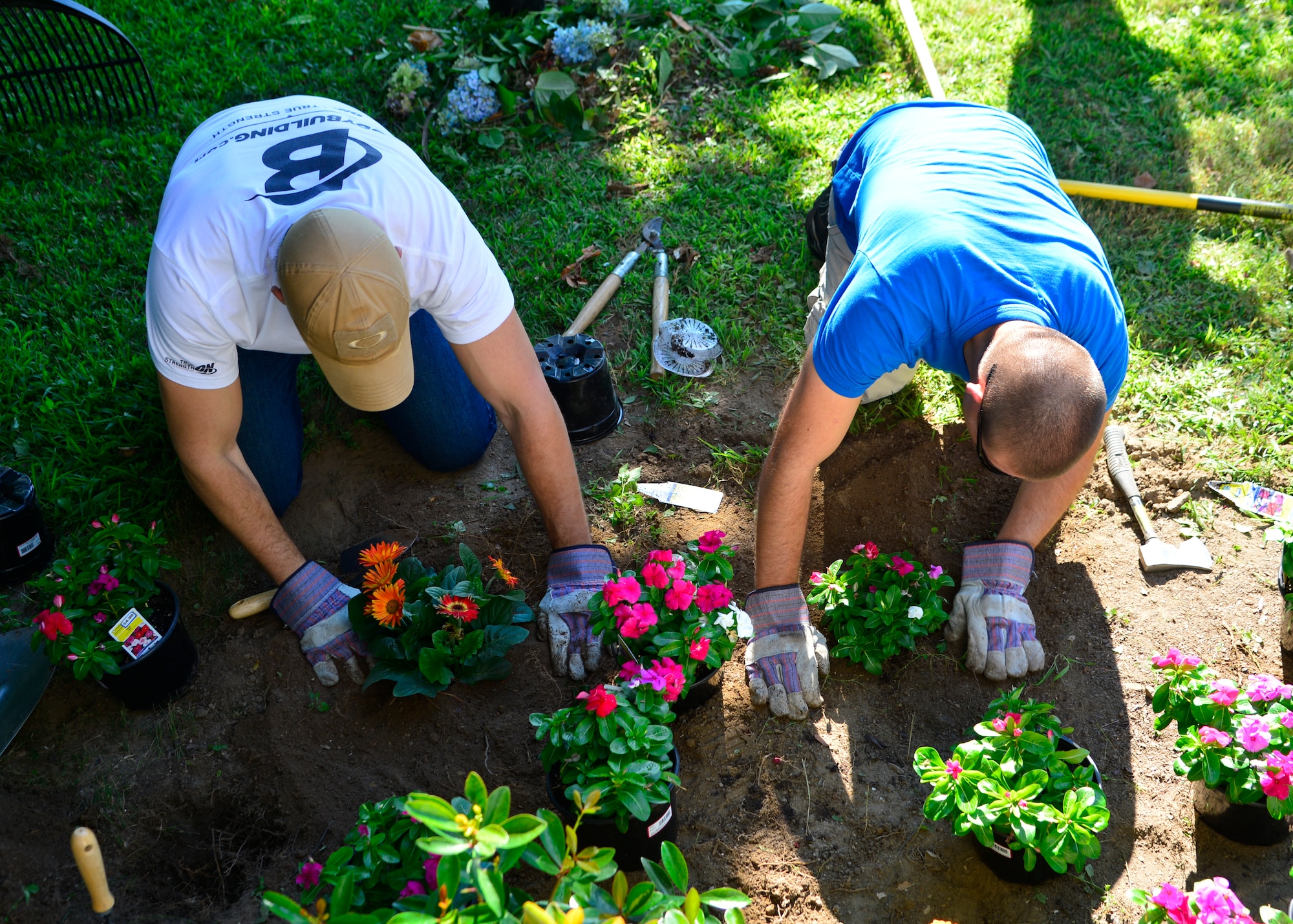 Senior Airman Bradley Harris, left, and Senior Airman Dustin Adkins, Airman Leadership School students, plant flowers in front of the Shepherd Place during a class volunteer project July, 25, 2015, in Dover, Del. Students replaced old, dying bushes with new flowers and plants, giving the shelter a welcoming exterior. (U.S. Air Force photo/Airman 1st Class William Johnson)