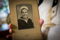 Lloyd Peterson, U.S. Navy World War II veteran, holds a photo of himself from 1944 at his home in Carpio, N.D., July 10, 2015. At the height of the war, Peterson operated LVCP amphibious vehicles in the Pacific Ocean surrounding Iwo Jima. (U.S. Air Force photo/Senior Airman Apryl Hall)