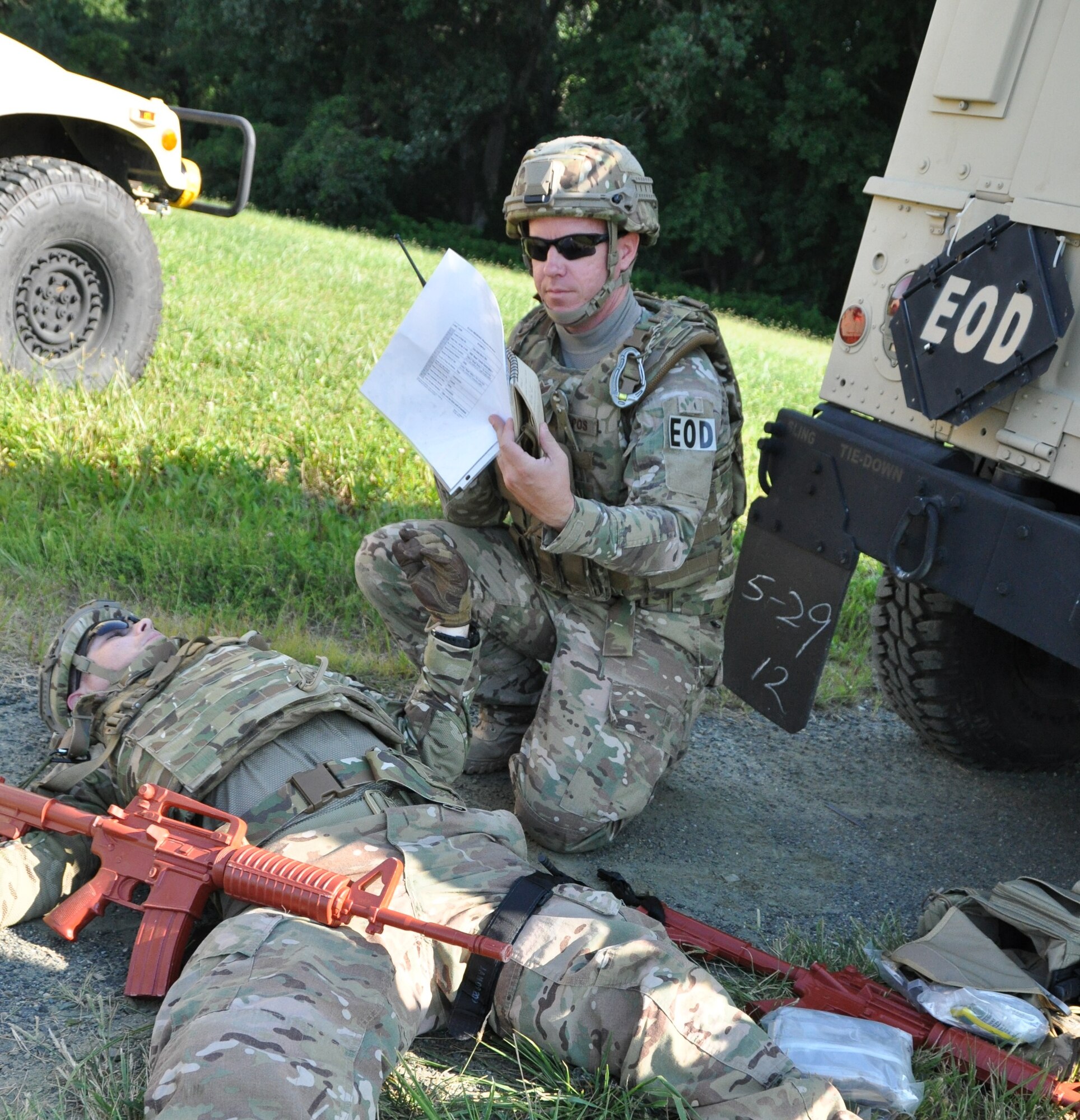 During a conventional weapons disposal training exercise, Staff Sgt. John Nelson (right), a 512th Explosive Ordnance Disposal Flight EOD technician, uses a 9-line form to call in a mock medical evacuation unit for his team leader, Staff Sgt. Charles Hall, 512th CES EOD, Aug. 1, 2015, at Dover Air Force Base, Del. Evaluators graded Nelson as he demonstrated administering first-aid buddy care to Hall, who pretendingly suffered from a sniper shot wound. (U.S. Air Force photo/Staff Sgt. Joe Yanik)  