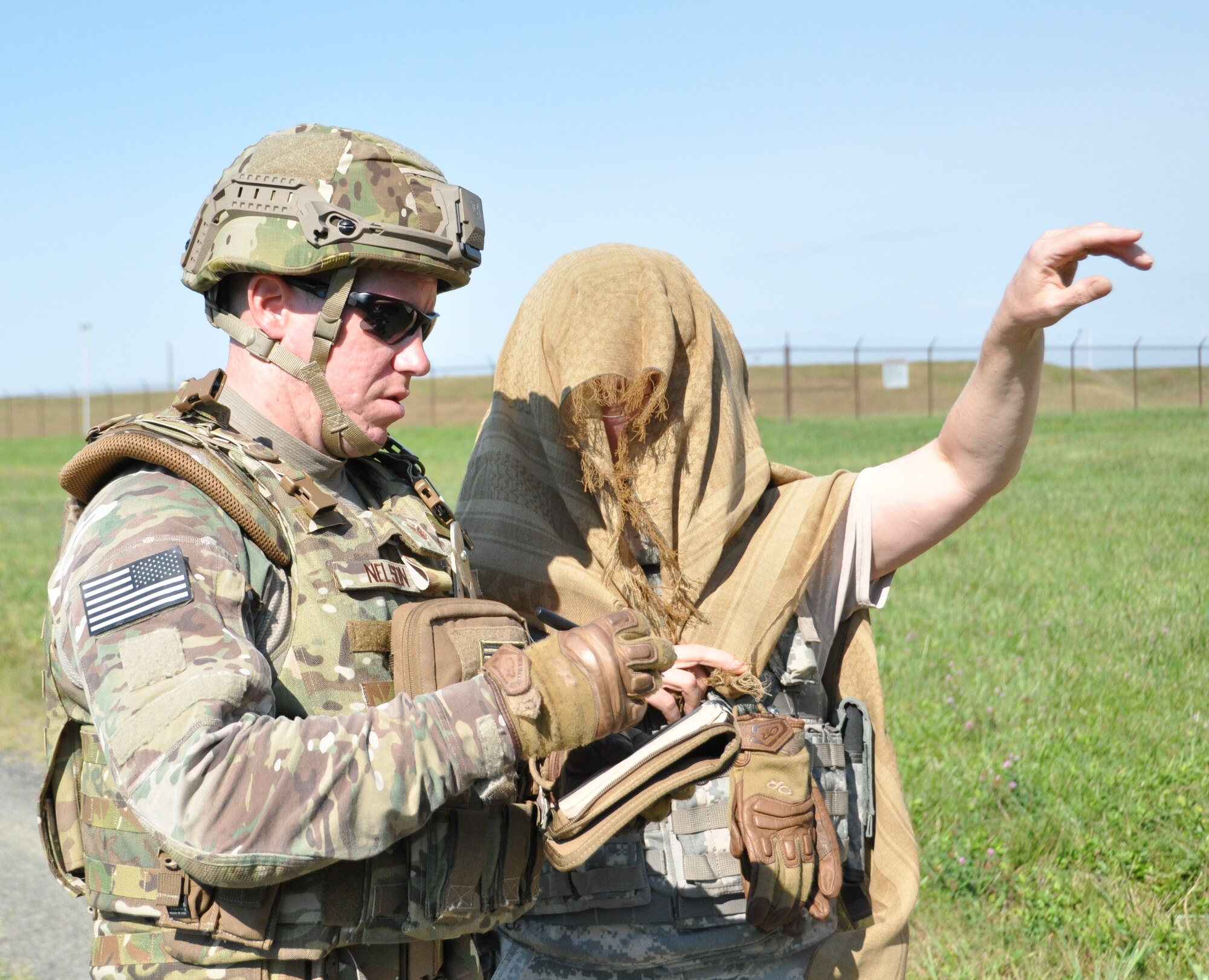 During a conventional weapons disposal training exercise, Staff Sgt. John Nelson (left), a 512th Explosive Ordnance Disposal Flight EOD technician, simulates gathering intelligence from Master Sgt. Mary Kokoszka, a 512th EOD program manager, who was posing as a foreign national village elder, Aug. 1, 2015, at Dover Air Force Base, Del. From a distance, evaluators graded Nelson on how he used the collected intelligence to locate a simulated weapons cache placed by mock enemy combatants in a staged forward operating area. (U.S. Air Force photo/Staff Sgt. Joe Yanik) 