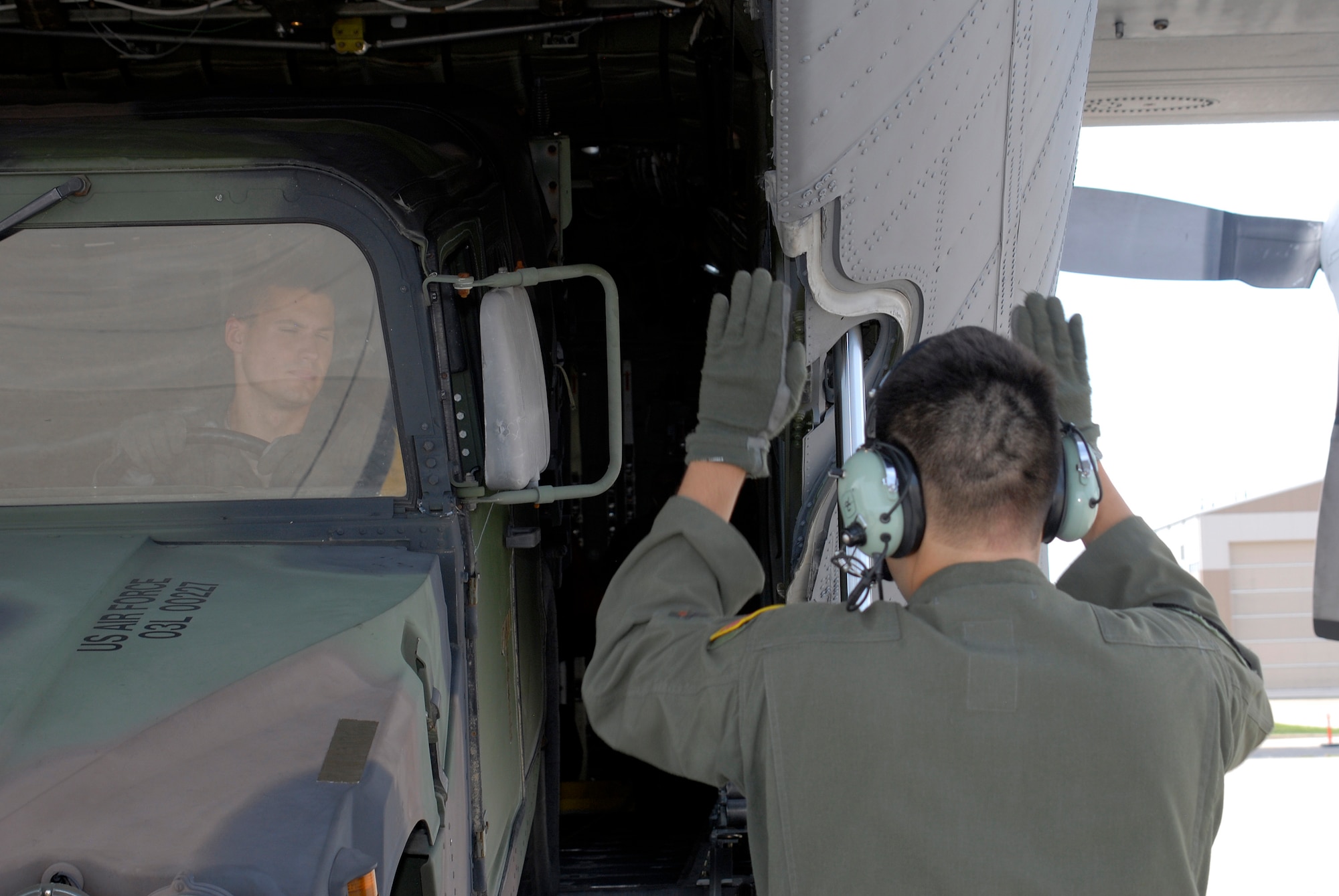 A loadmaster with the 169th Airlift Squadron, marshals a Humvee down a C-130 ramp during training at the 182nd Airlift Wing, Peoria, Ill., Aug. 1, 2015. The training was conducted to ensure that the loadmasters are always on mission and ready for real-world scenarios. (U.S. Air National Guard photo by Tech. Sgt. Dawn Rademaker/Released)