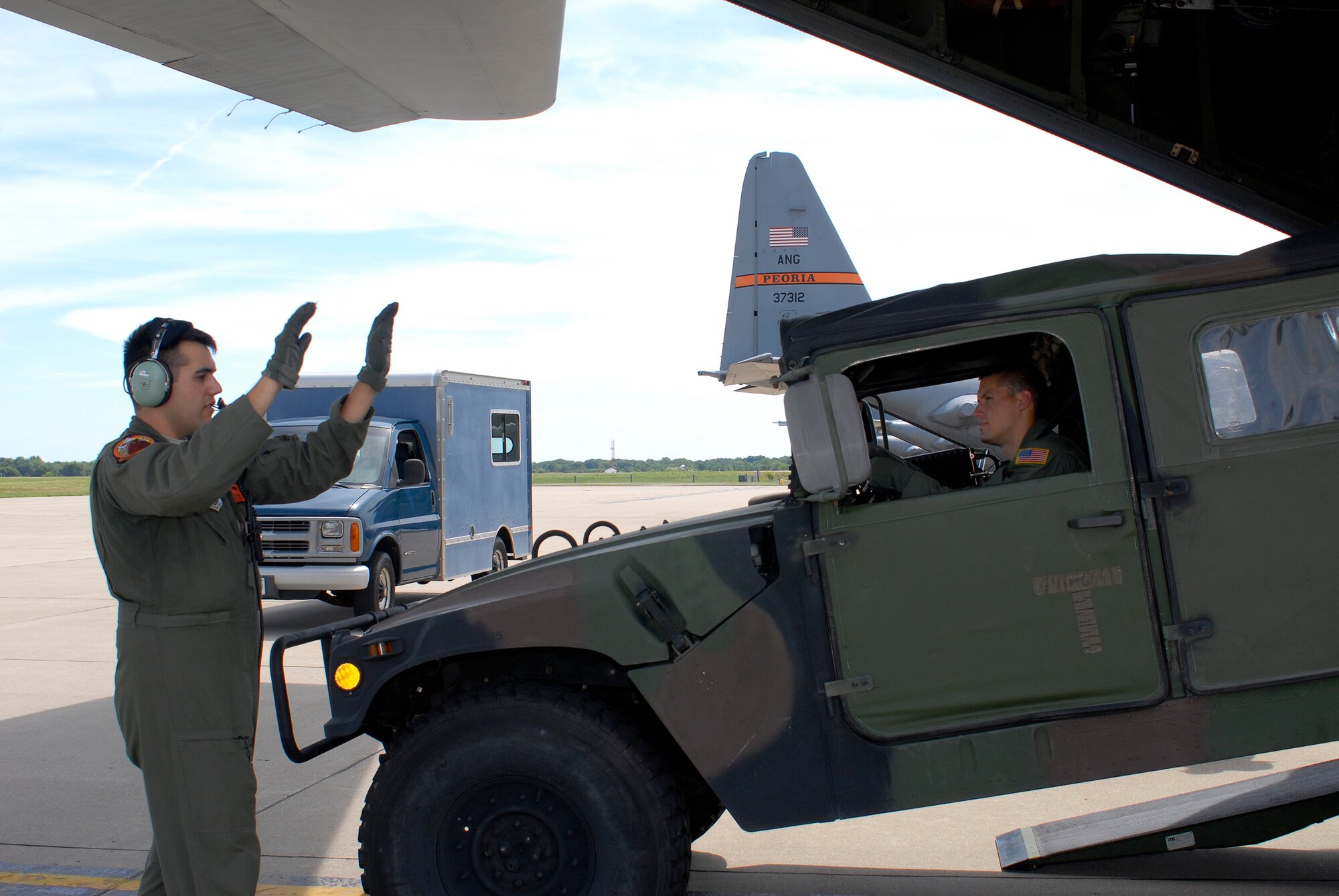 A loadmaster with the 169th Airlift Squadron, marshals a Humvee down a C-130 ramp during training at the 182nd Airlift Wing, Peoria, Ill., Aug. 1, 2015. The training was conducted to ensure that the loadmasters are always on mission and ready for real-world scenarios. (U.S. Air National Guard photo by Tech. Sgt. Dawn Rademaker/Released)