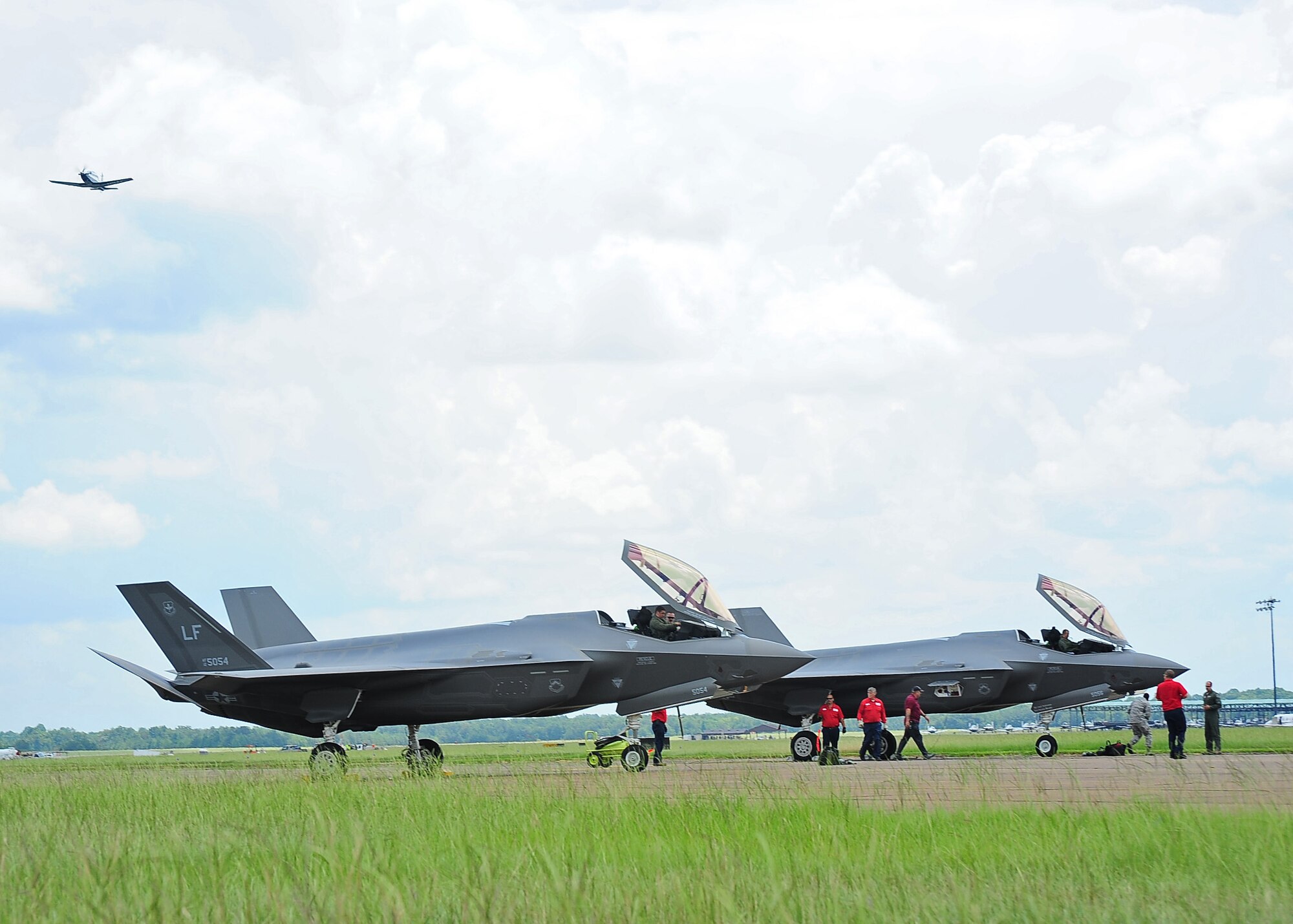 A T-6 Texan II roars overhead as the pilots of two Luke Air Force Base F-35 Lightning IIs prepare to exit their aircraft July 23 at the Columbus Air Force Base, Mississippi. The pilots were Capt. Nicholas Rallo, left, 62nd Fighter Squadron, and Brig. Gen. Scott Pleus, 56th Fighter Wing commander. Pleus spoke to the media about the visit and later gave two briefings to Columbus' Airmen about the F-35’s capabilities. He also served as the guest speaker for the base's undergraduate pilot training graduation ceremony that night. The arrival marks the F-35's first visit to Columbus AFB. The visit served to inform the local community on the role of the service's newest fighter jet and educated the Air Force's newest pilots on an airframe they may be called upon to fly in combat now that they've graduated from UPT. 
